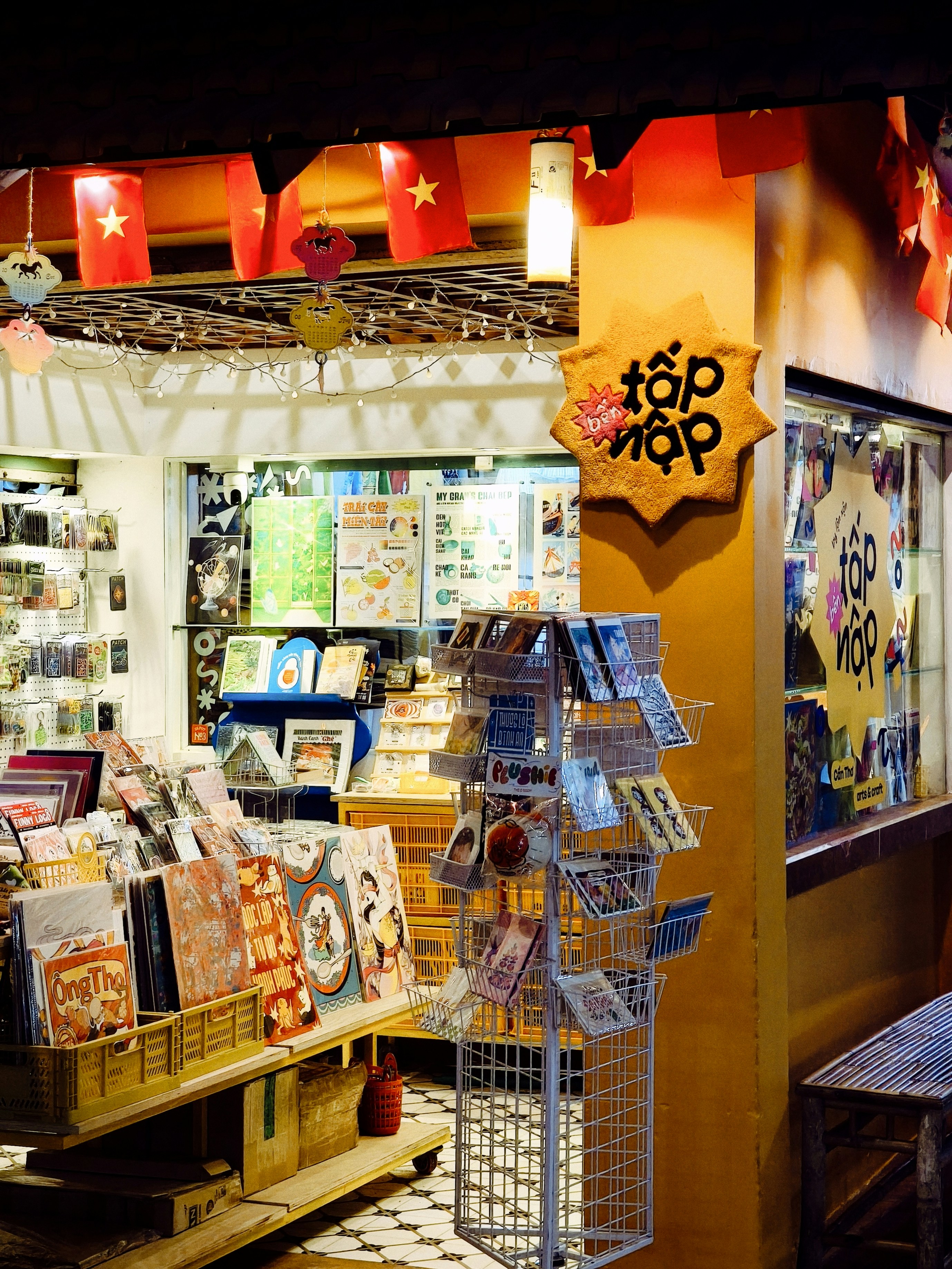 A small shop filled with books and stationery under red Vietnamese flags