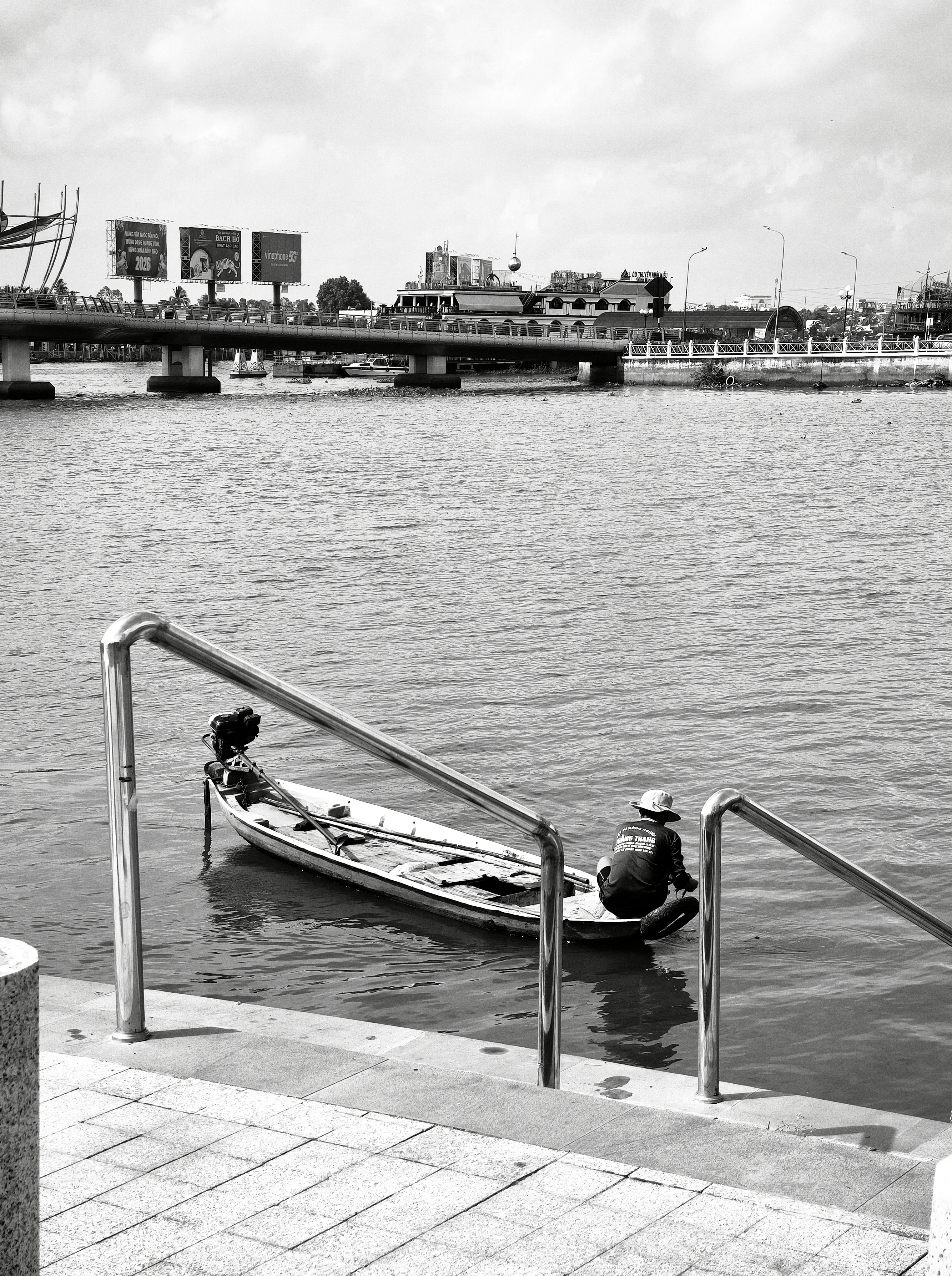 A person in a hat sitting in a small boat on a river