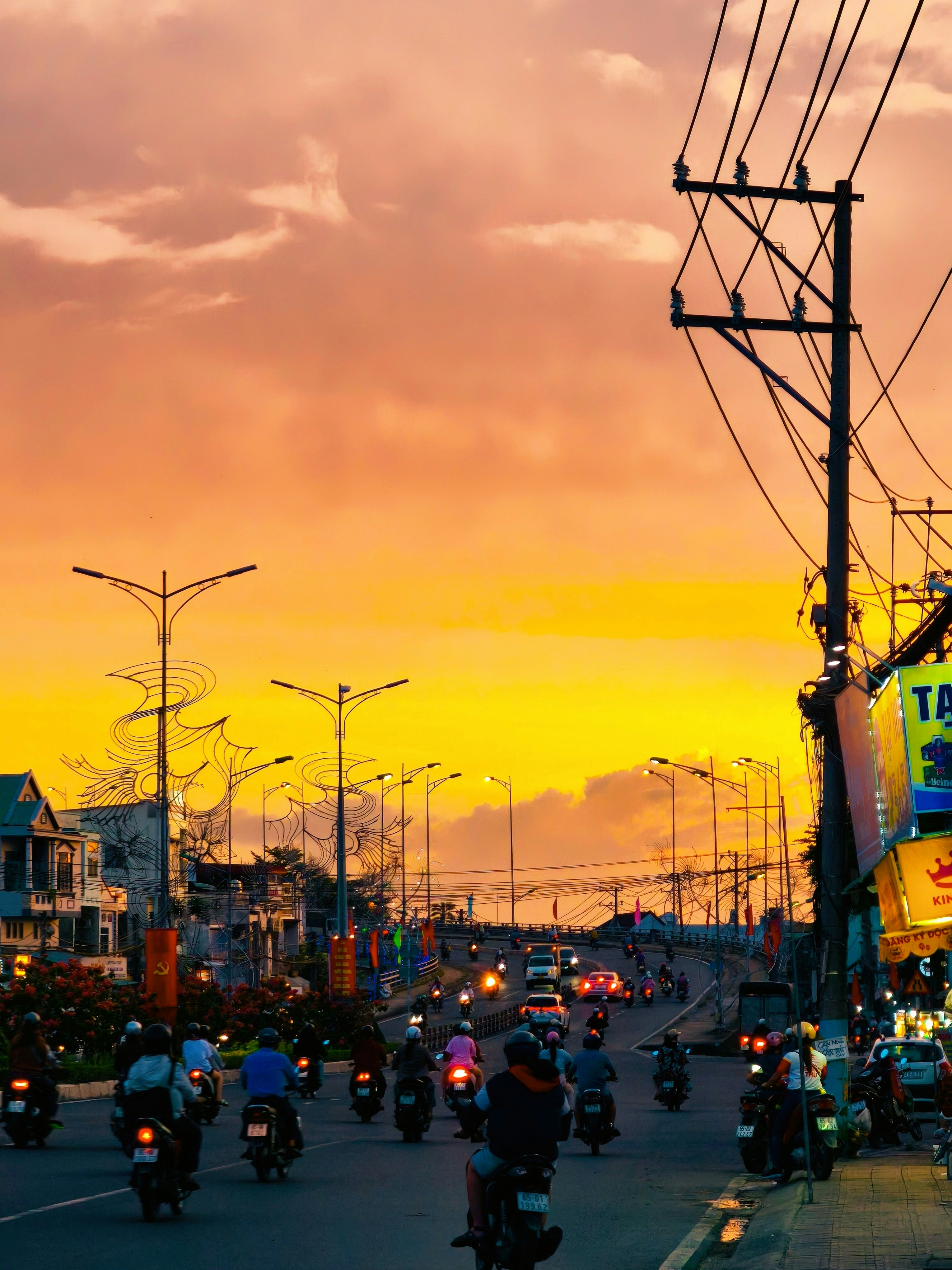 Motorcyclists riding on a city street under a vibrant orange and yellow sky