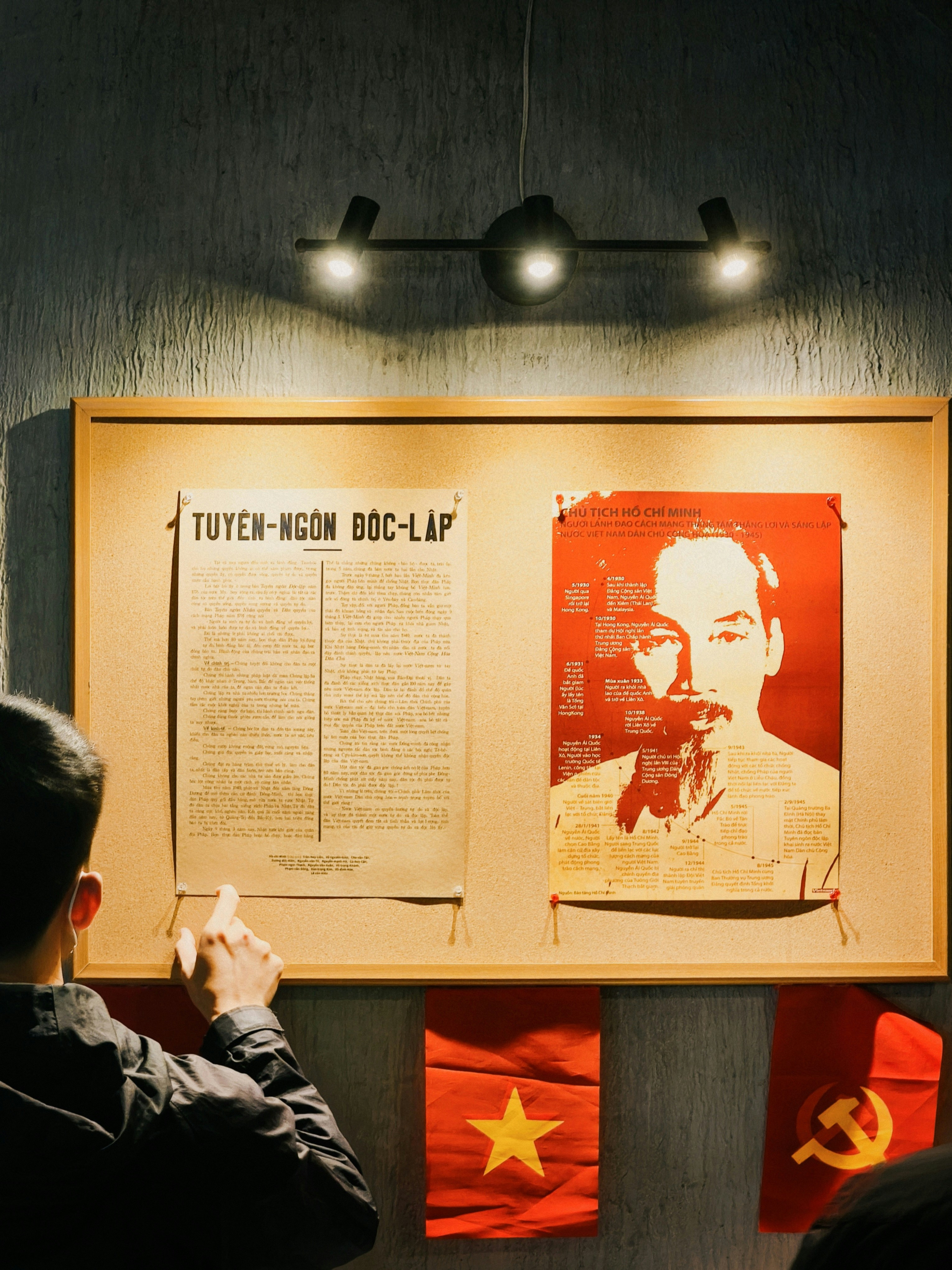 A person pointing at a historical document on a cork board with flags