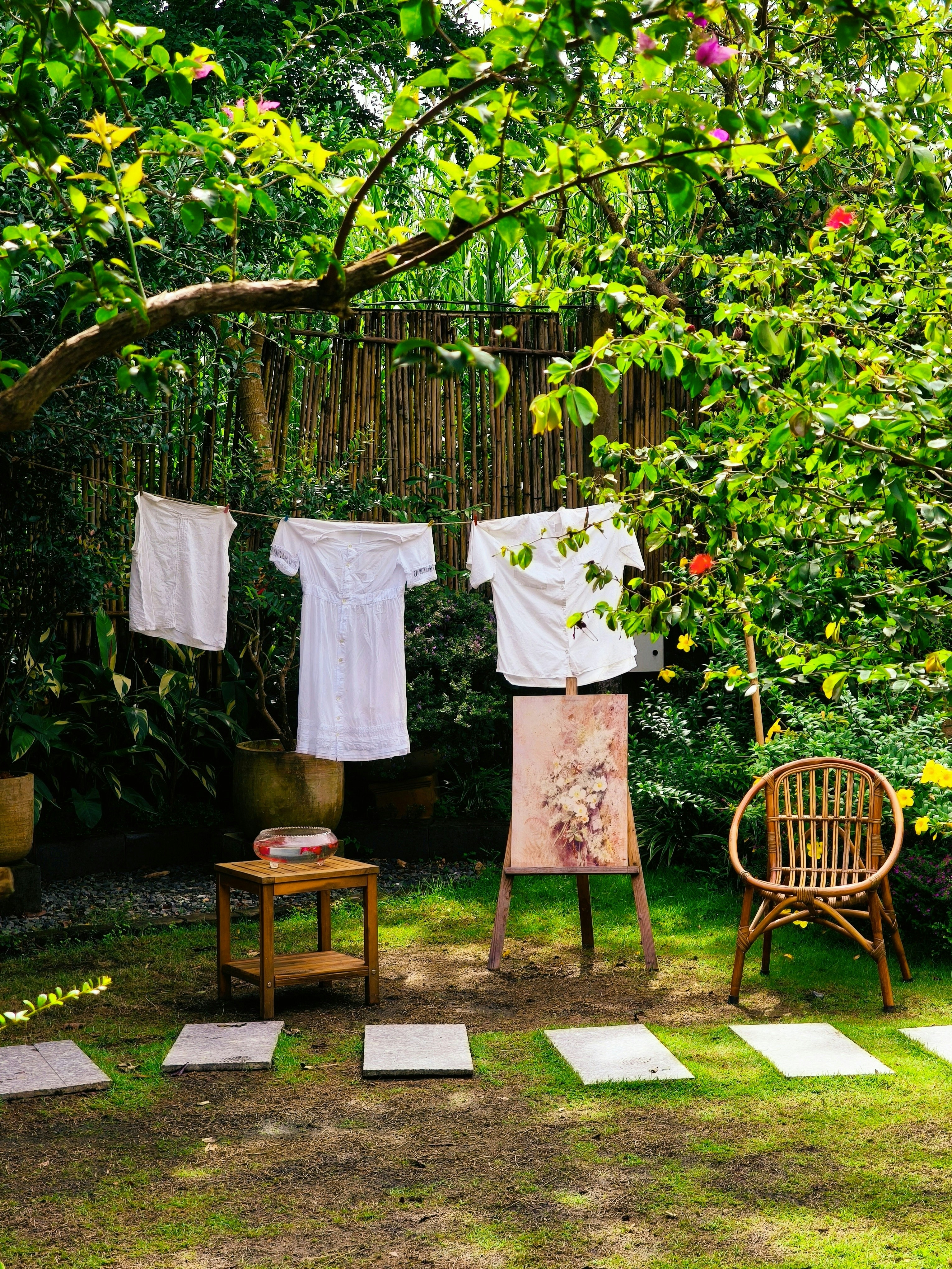 White clothes hanging on a line in a lush garden with a painting