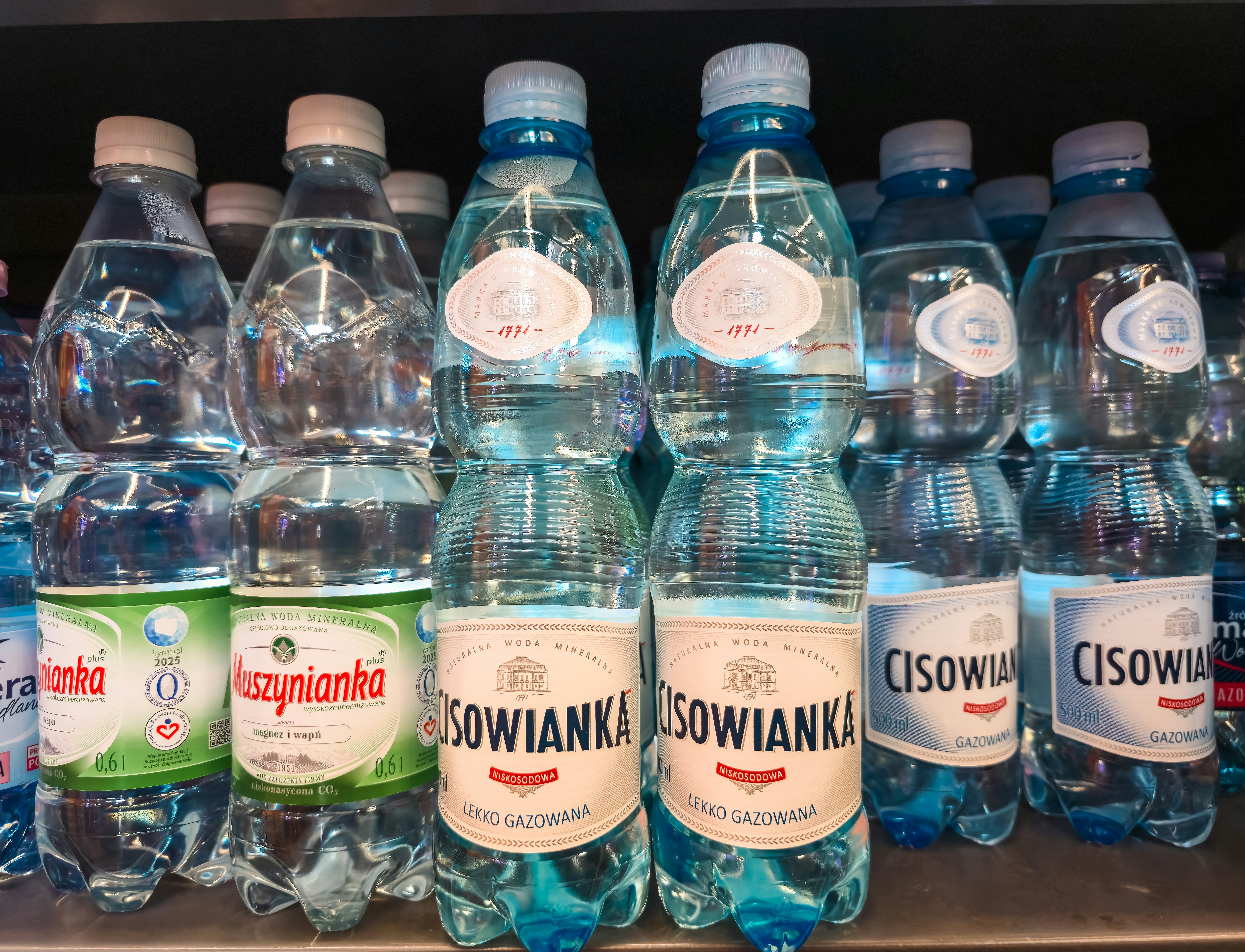 File di bottiglie d'acqua di plastica con tappi blu su uno scaffale del negozio