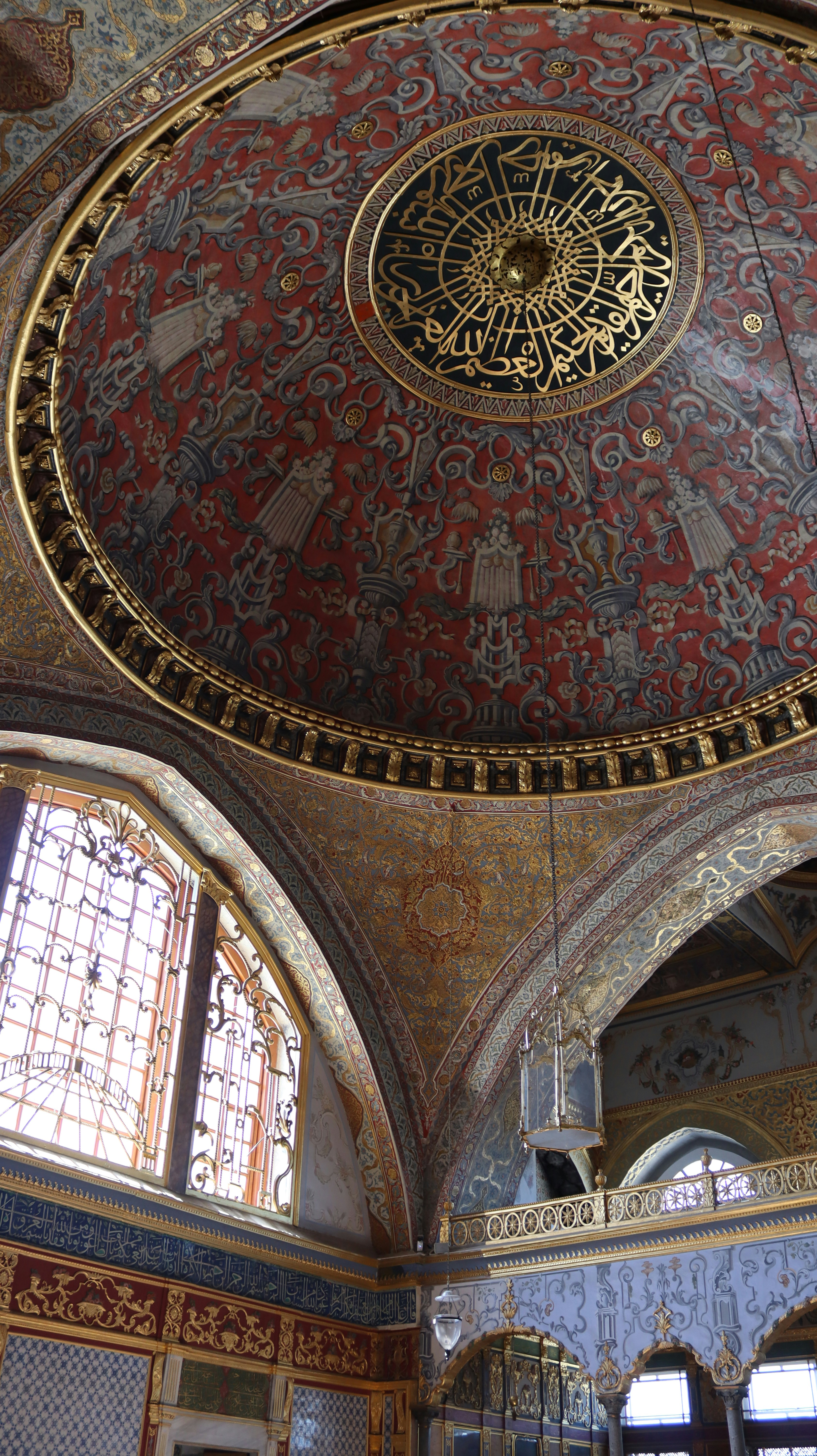 Ornate painted dome with gold calligraphy and intricate patterns inside a historic mosque