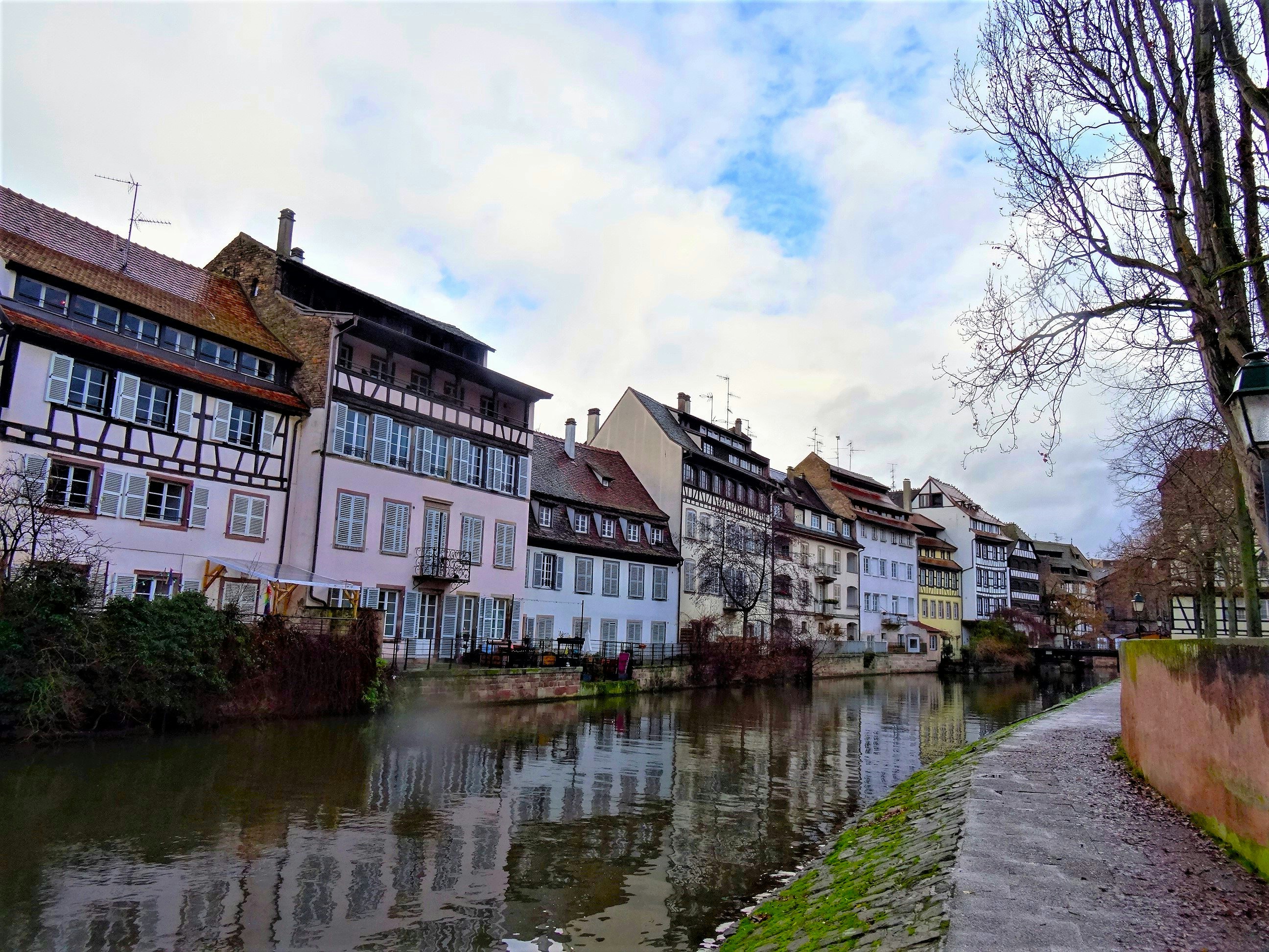 Maisons à colombages le long d'un canal à Strasbourg sous un ciel nuageux