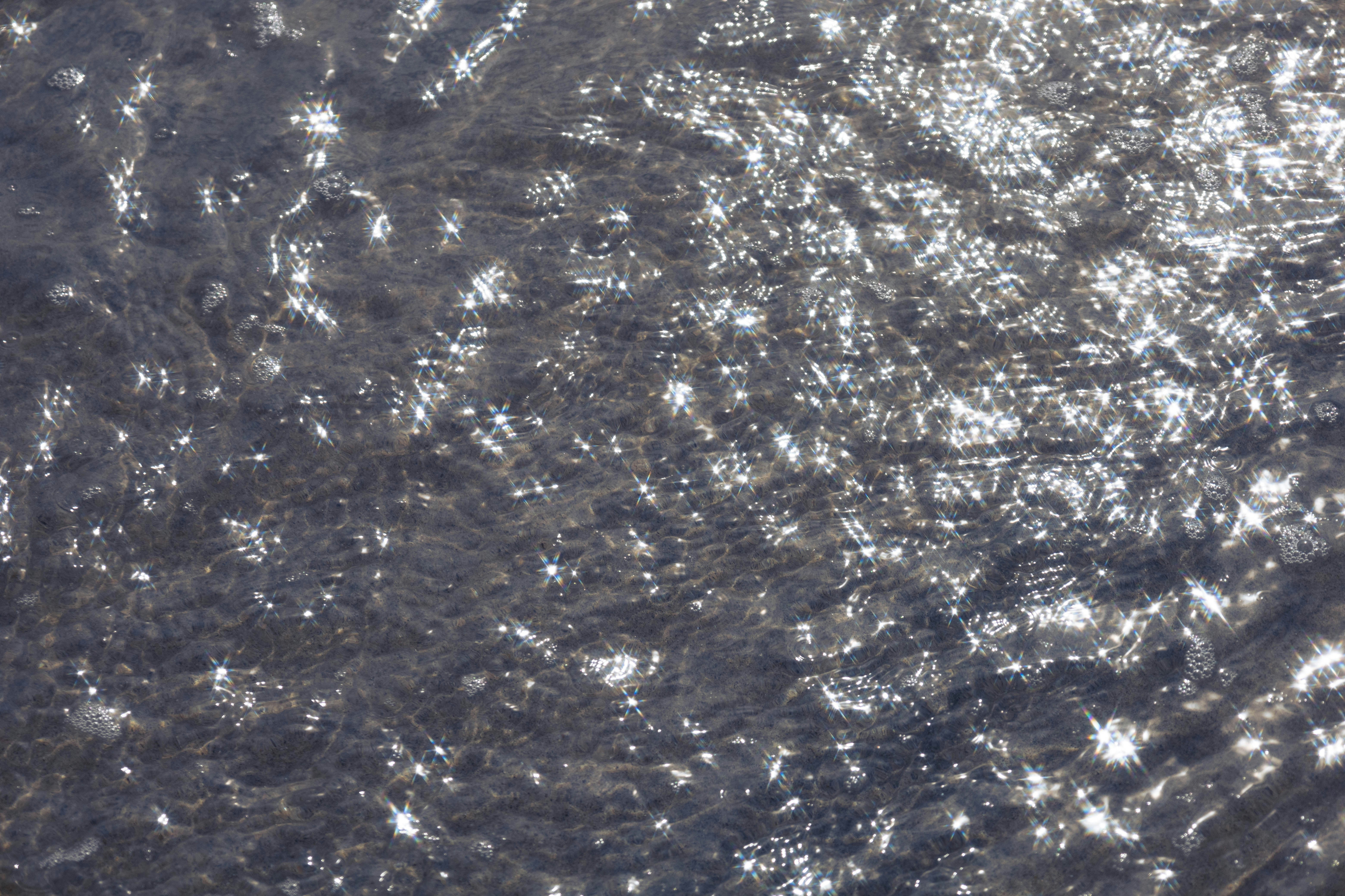 Sunlight reflecting off the surface of shallow water creating bright star-shaped glints