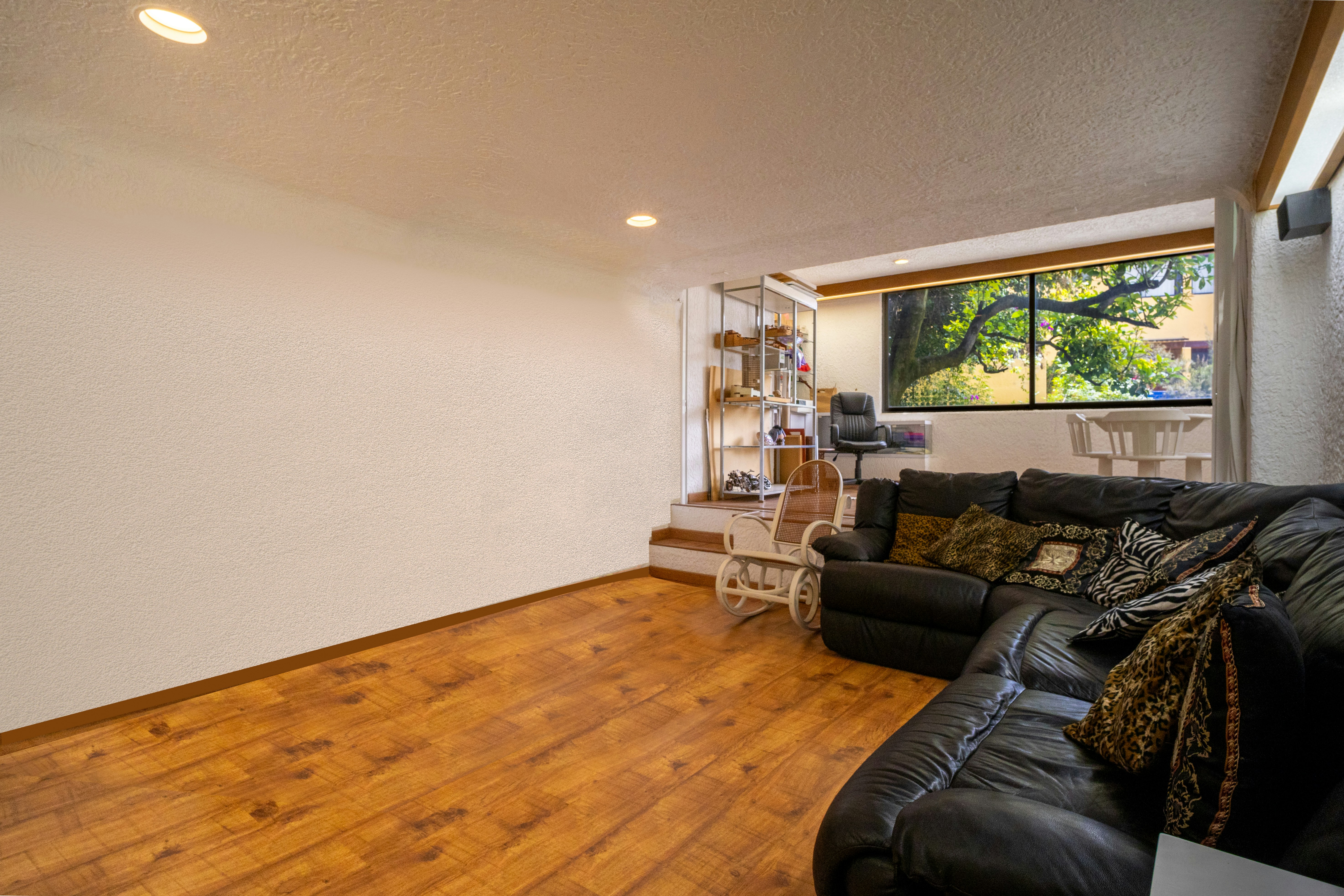 A black leather sectional sofa on a wooden floor in a living room