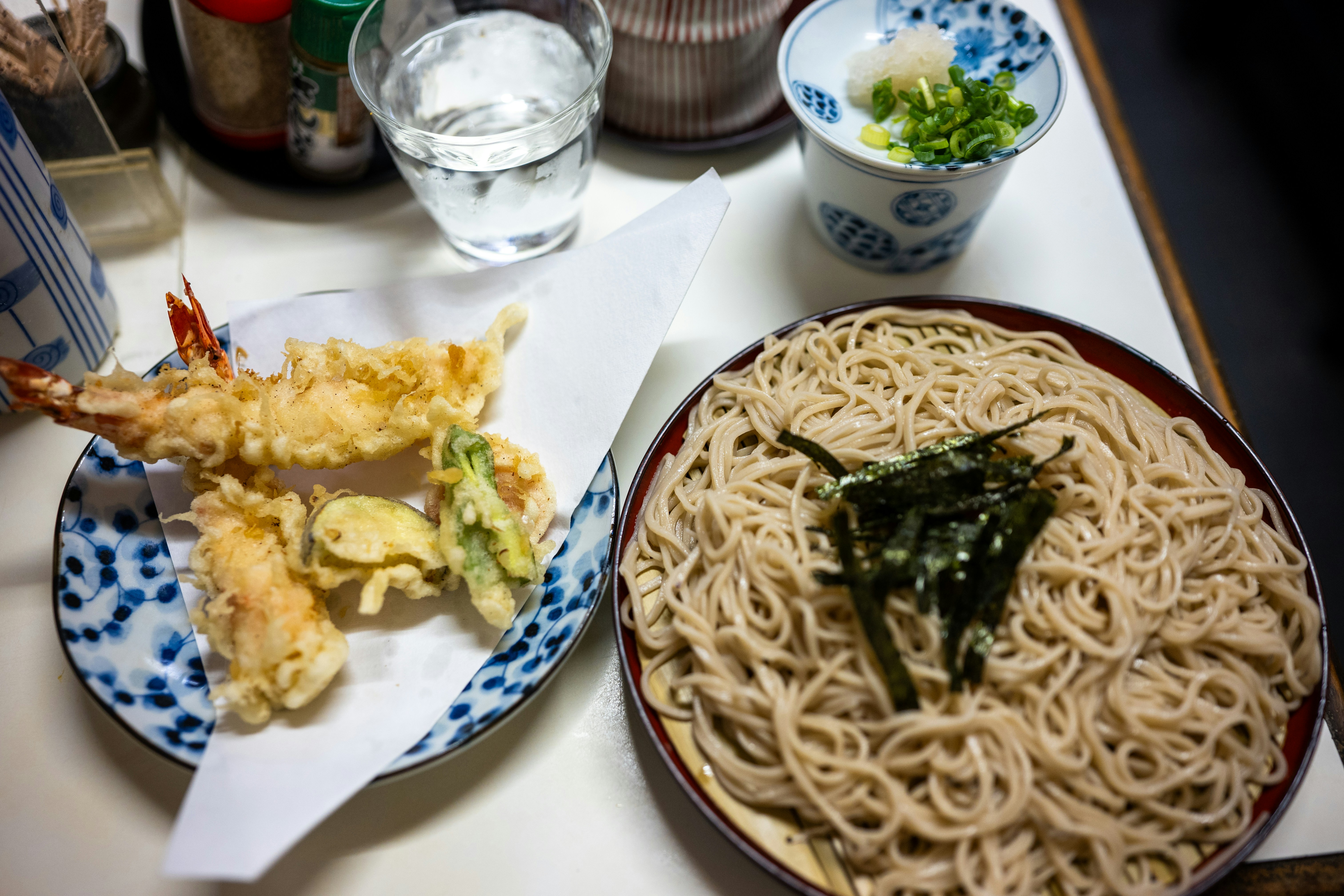 Tempura shrimp and vegetables beside a bowl of cold soba noodles with seaweed