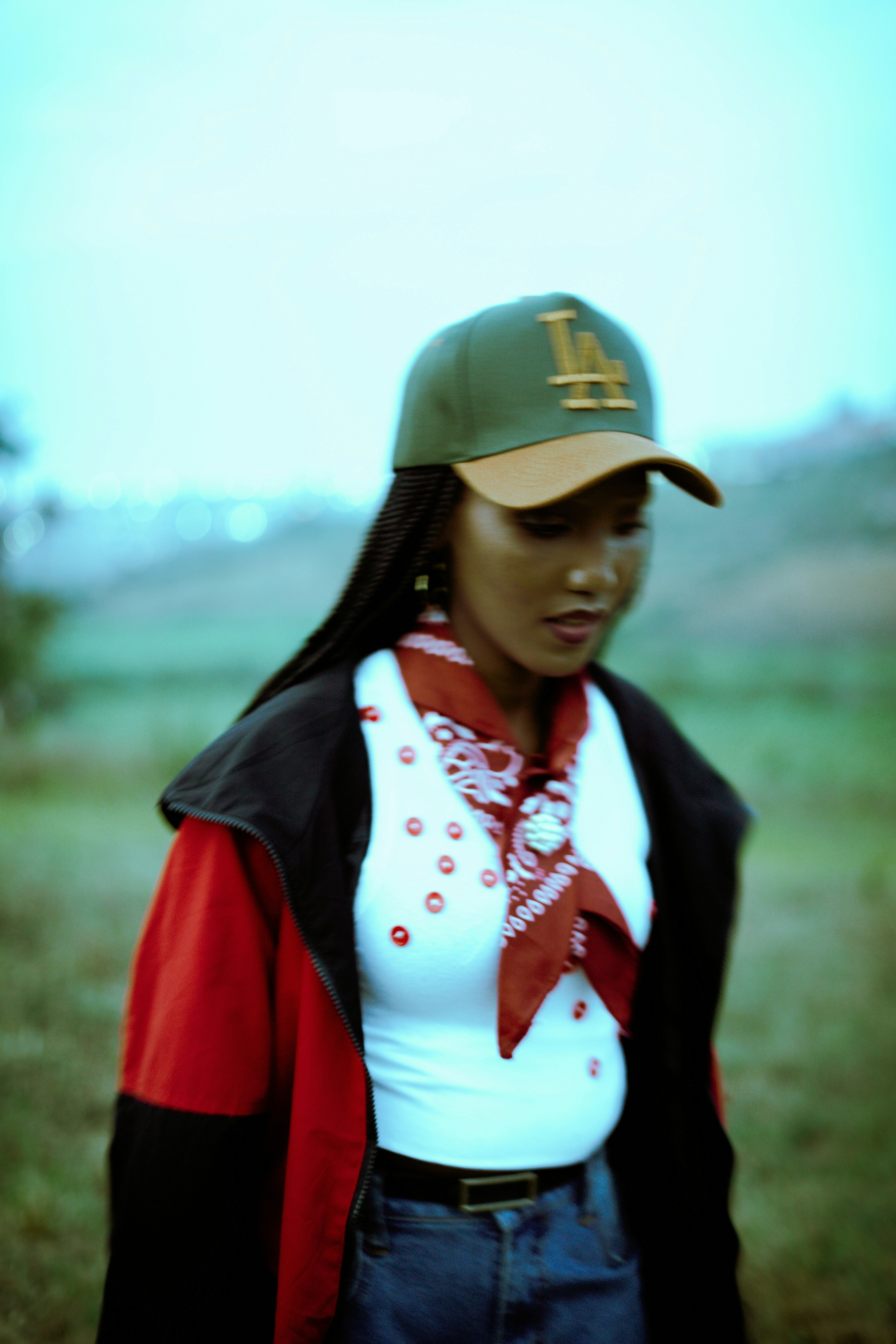 A woman wearing a green baseball cap, red jacket, and white top outdoors