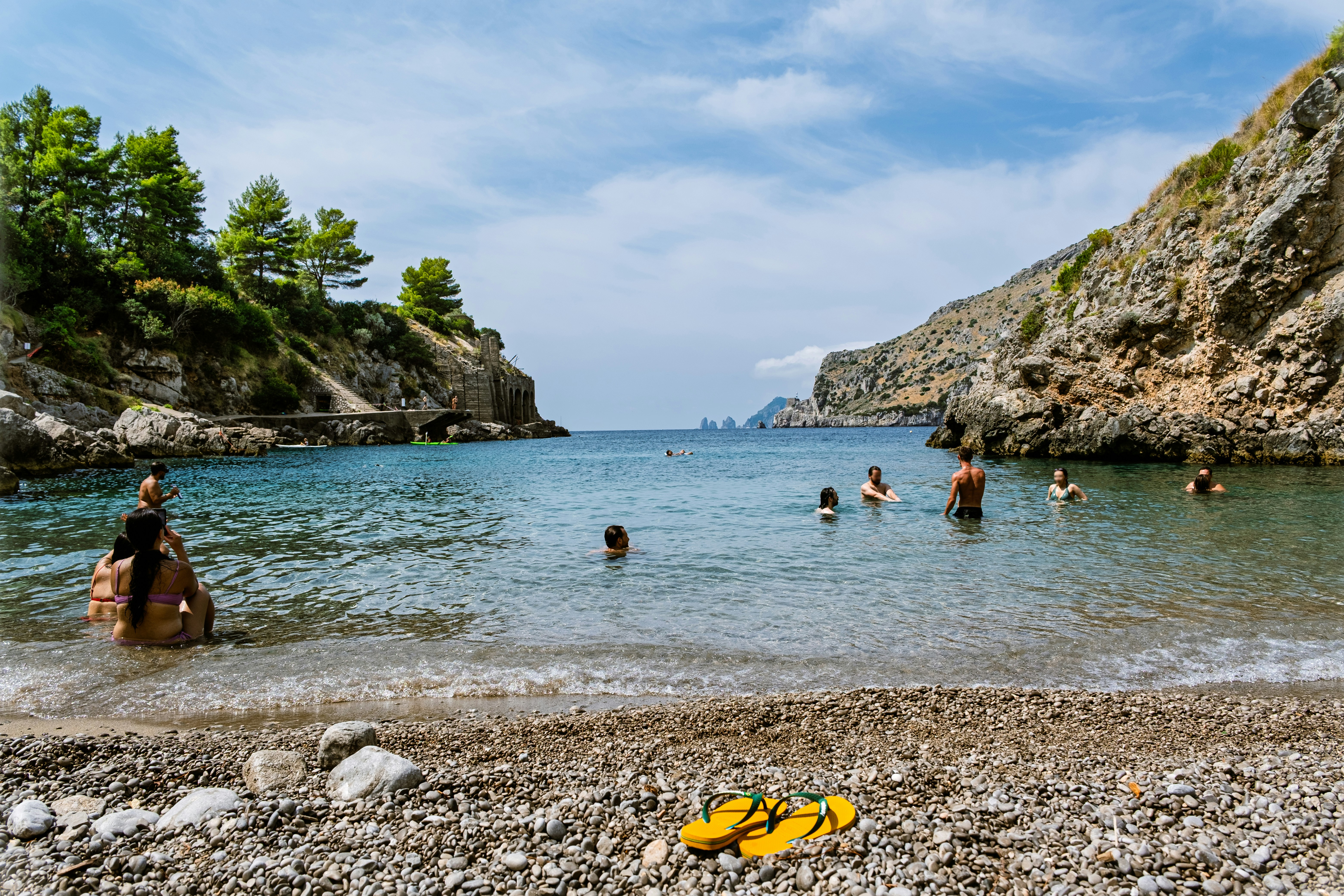 People swimming and relaxing on a pebble beach in a rocky cove