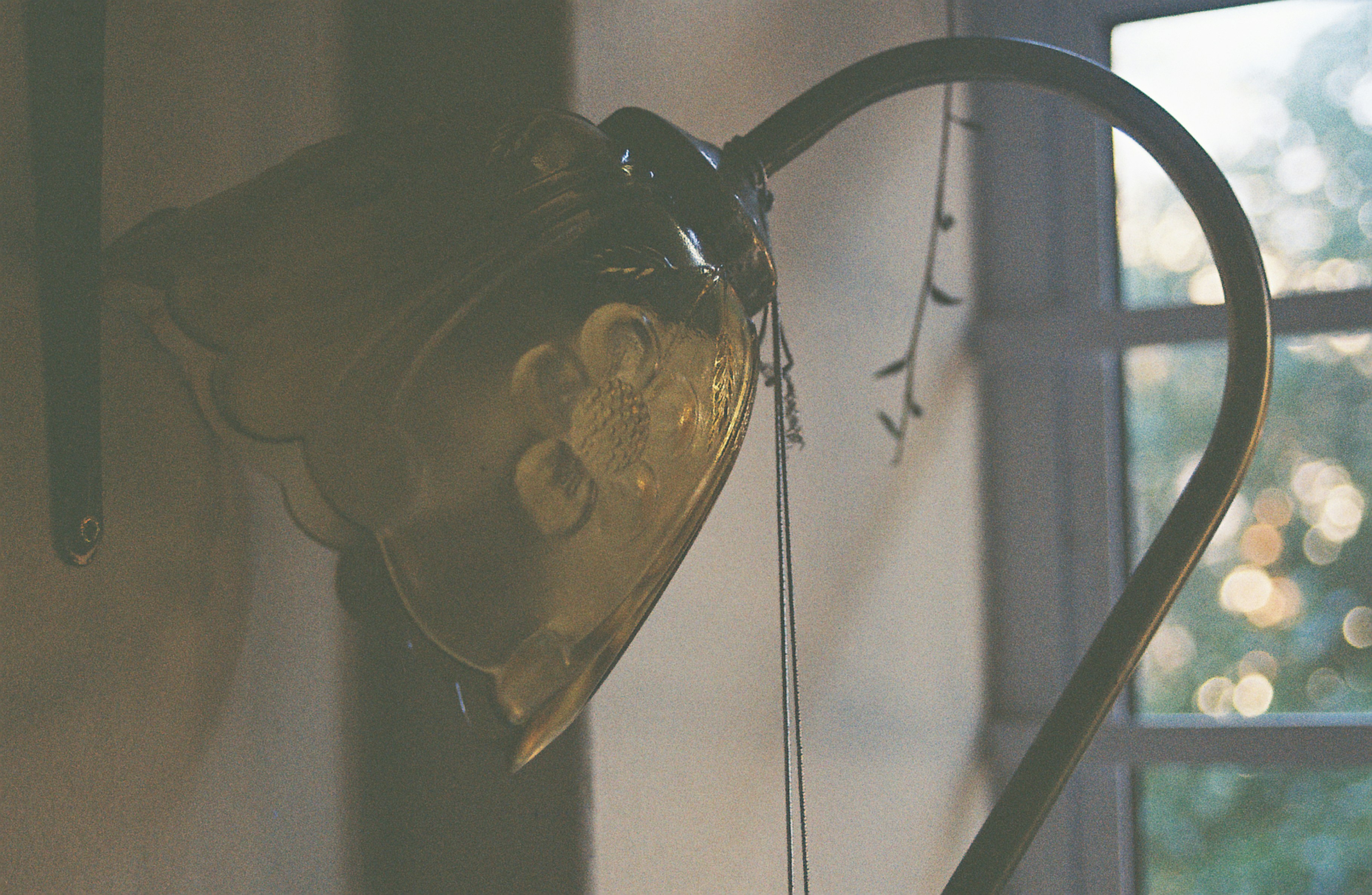 A vintage glass wall lamp with a floral pattern near a window