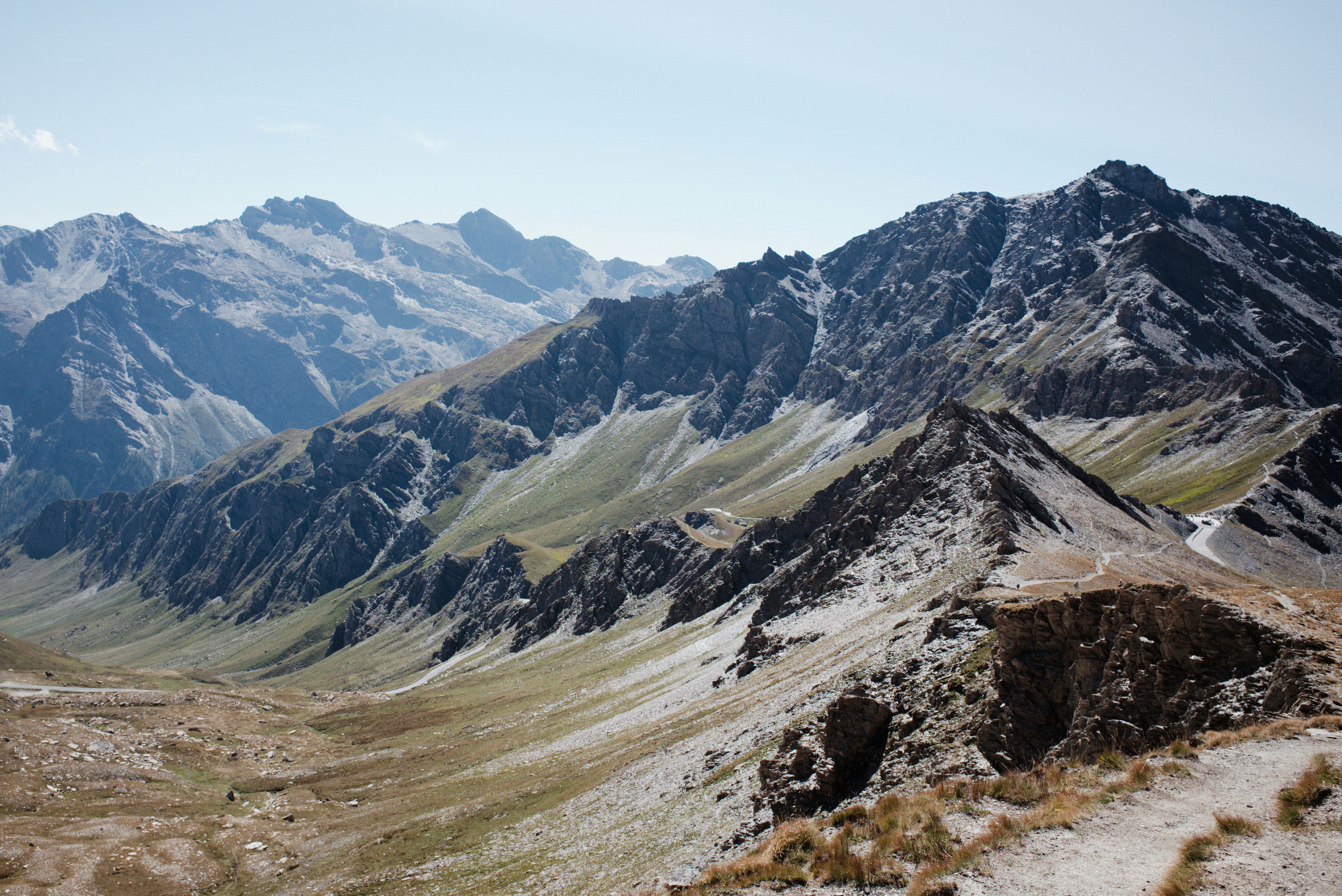 A winding mountain road through a rocky alpine valley under a clear sky