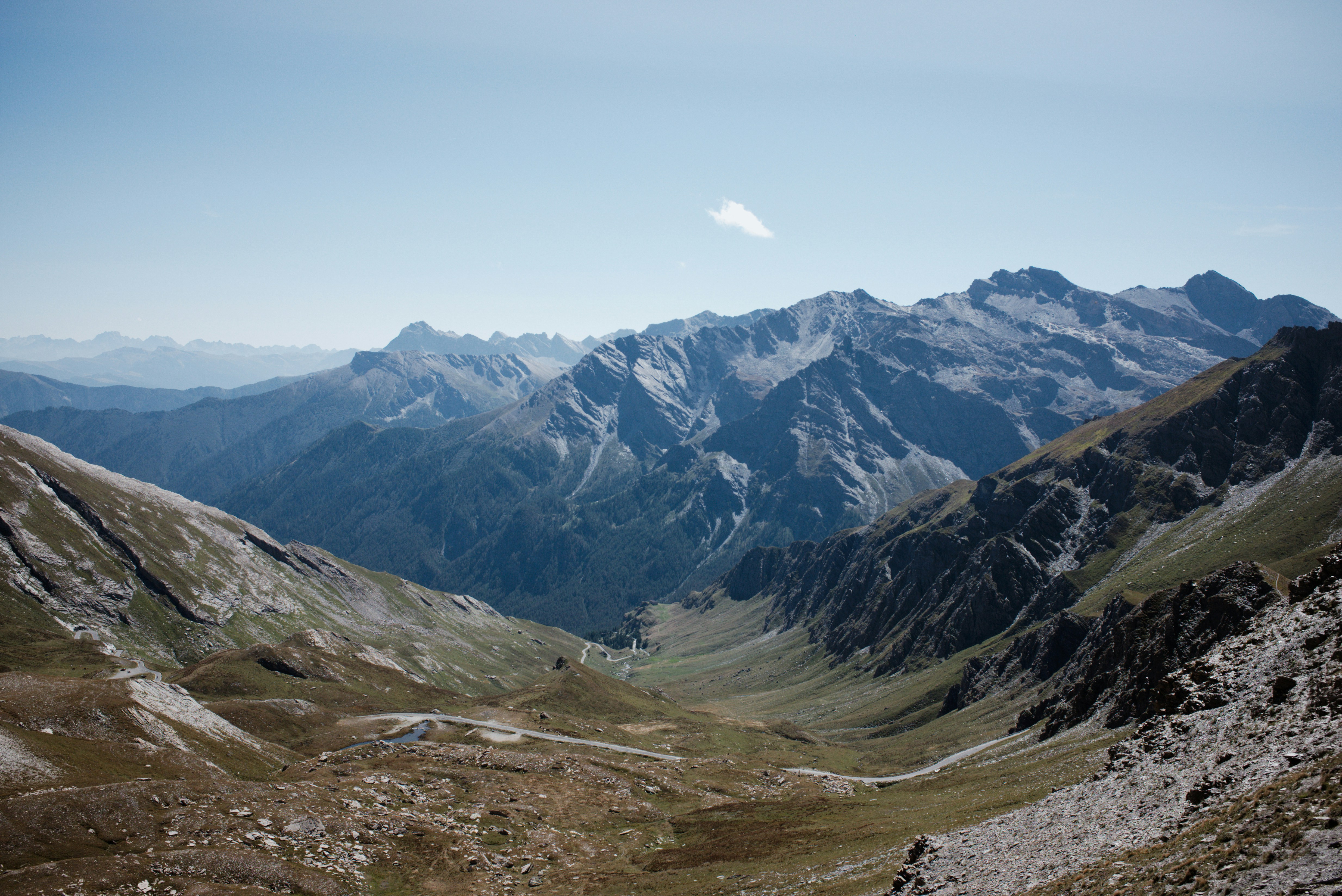 A winding road through a deep mountain valley beneath jagged rocky peaks
