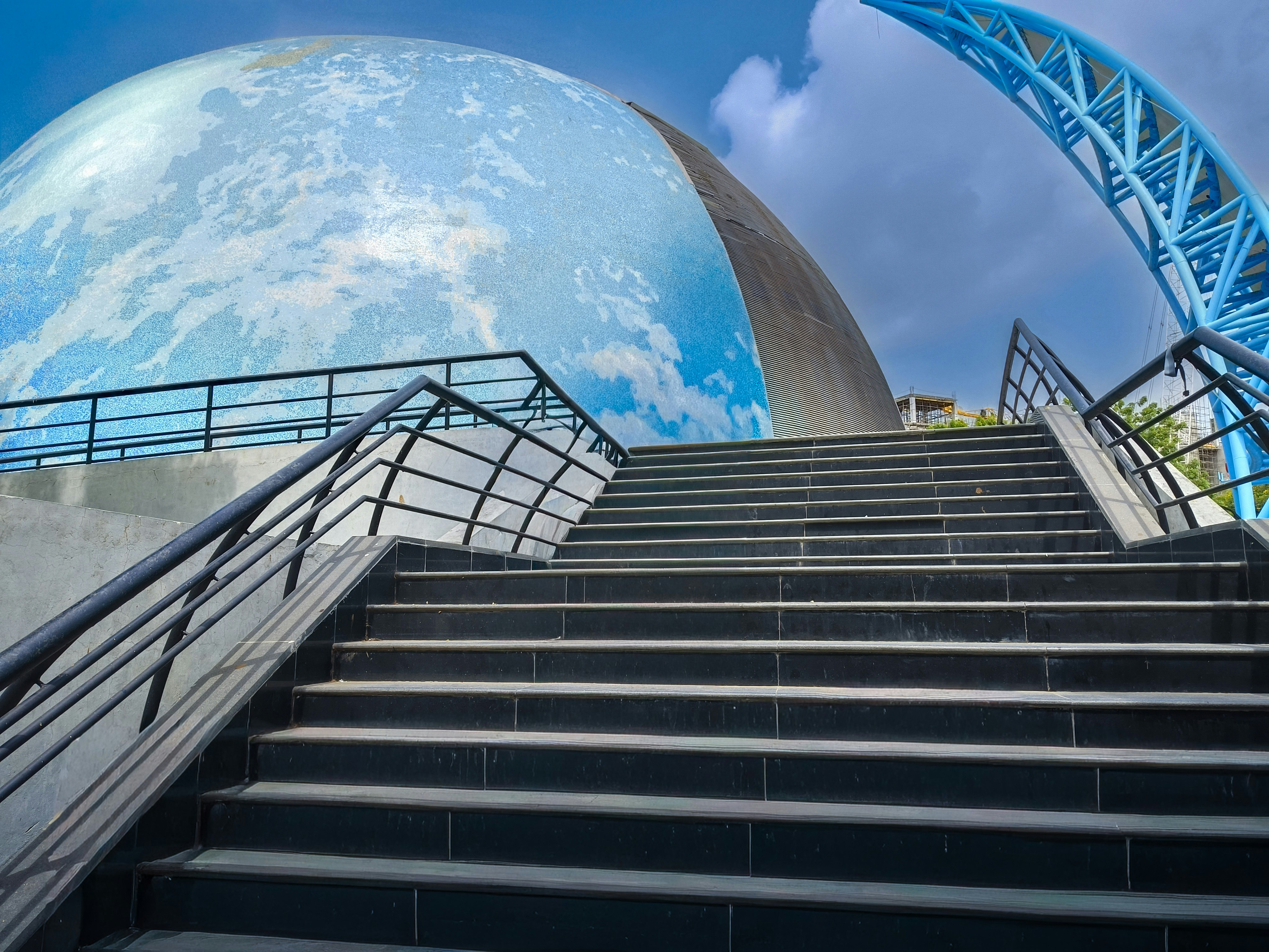 Black stairs leading up to a large dome with a blue sky pattern