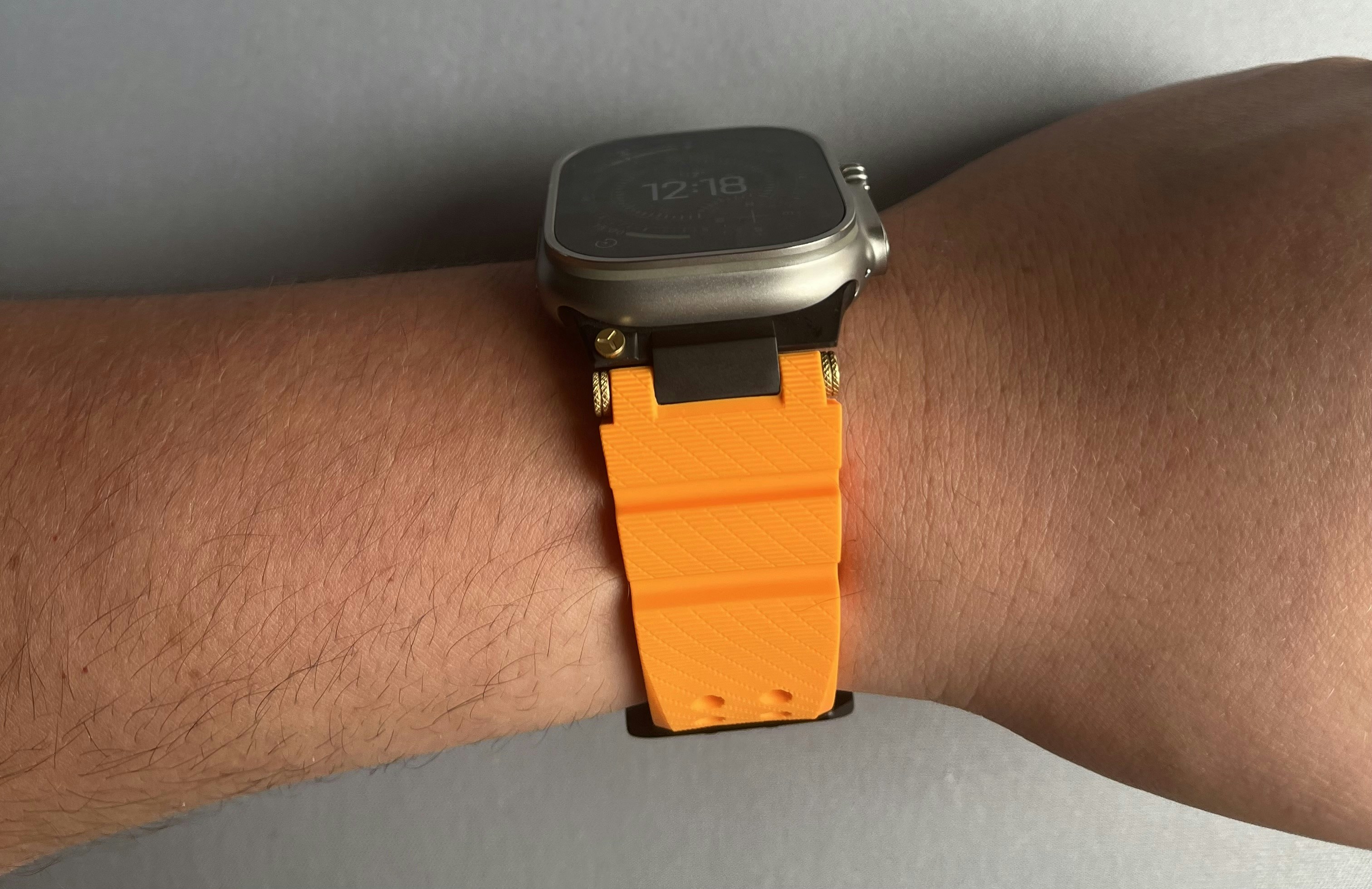 A smartwatch with a bright orange textured silicone band on a person's wrist