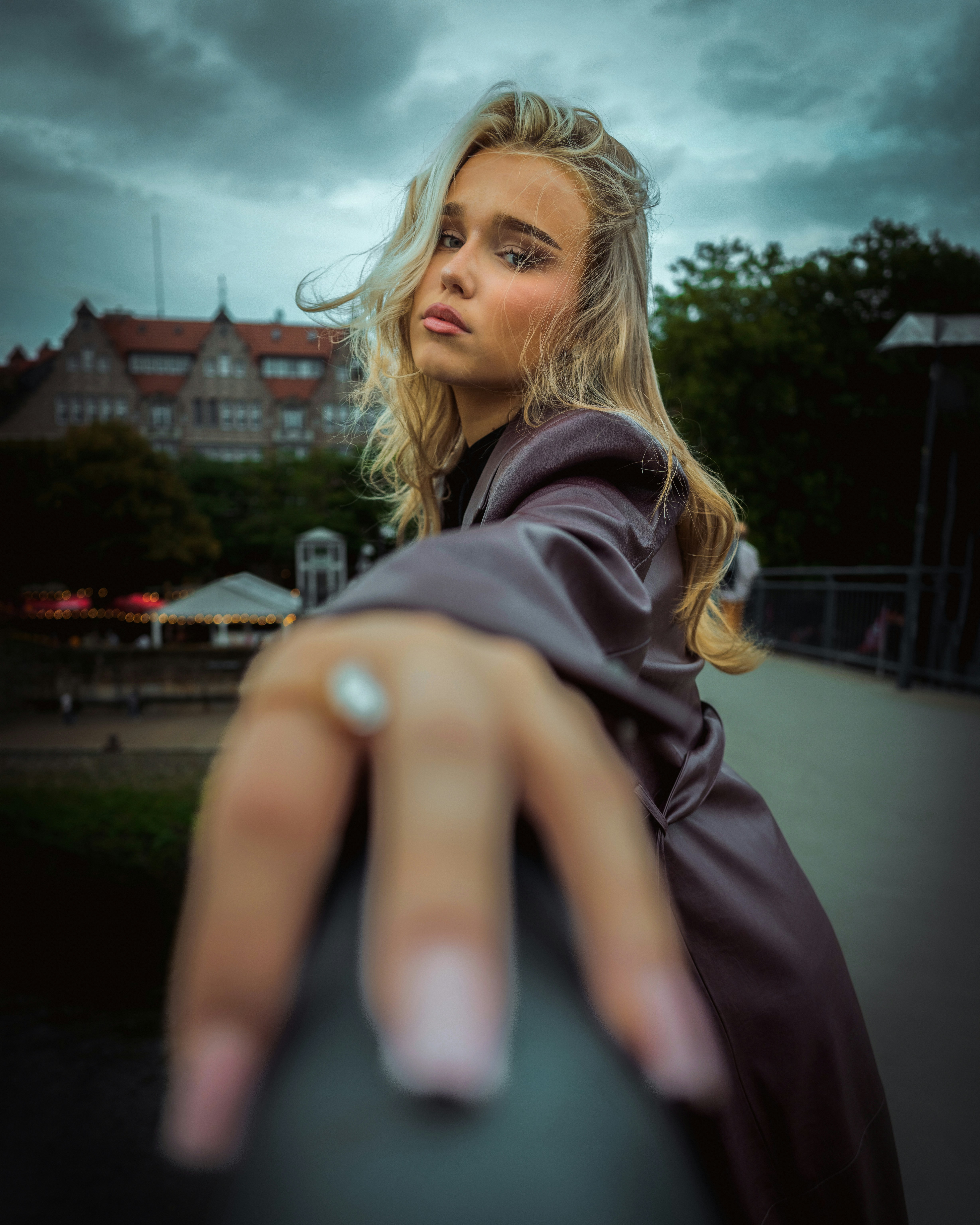 A woman with blonde hair in a dark coat reaching toward the camera