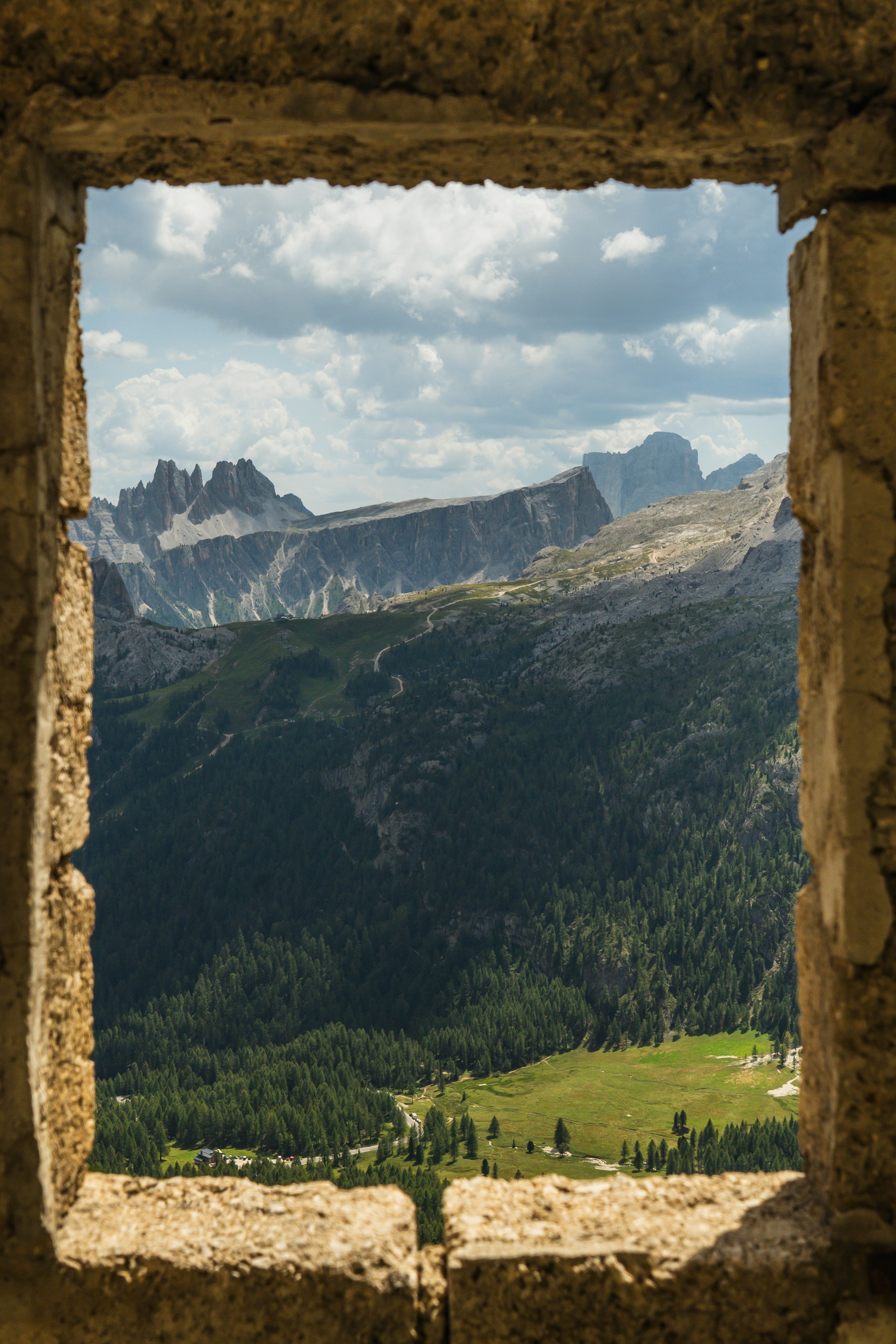 A view of the Dolomites through a rustic stone window frame