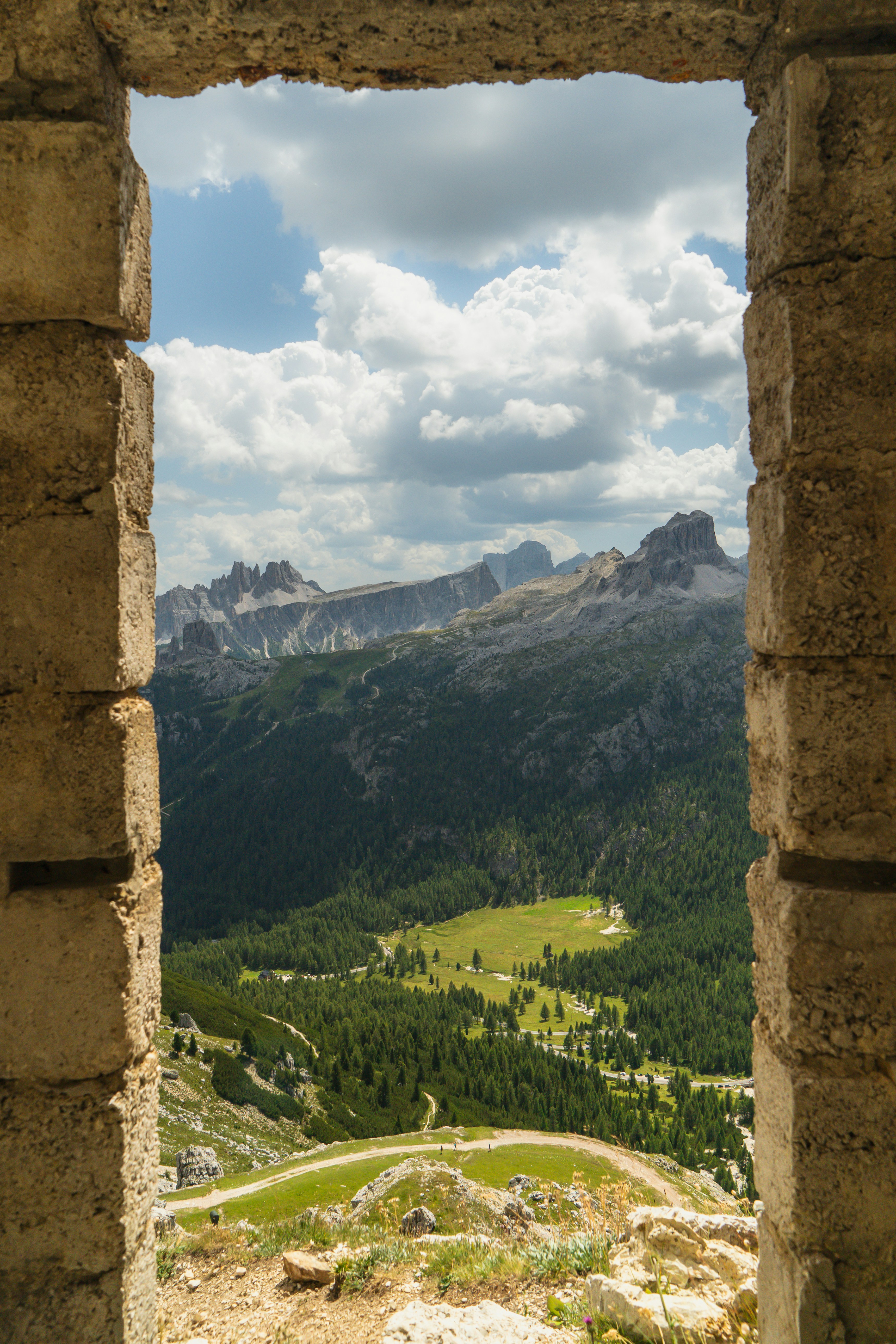 View of the Dolomite mountains through a rustic stone window frame