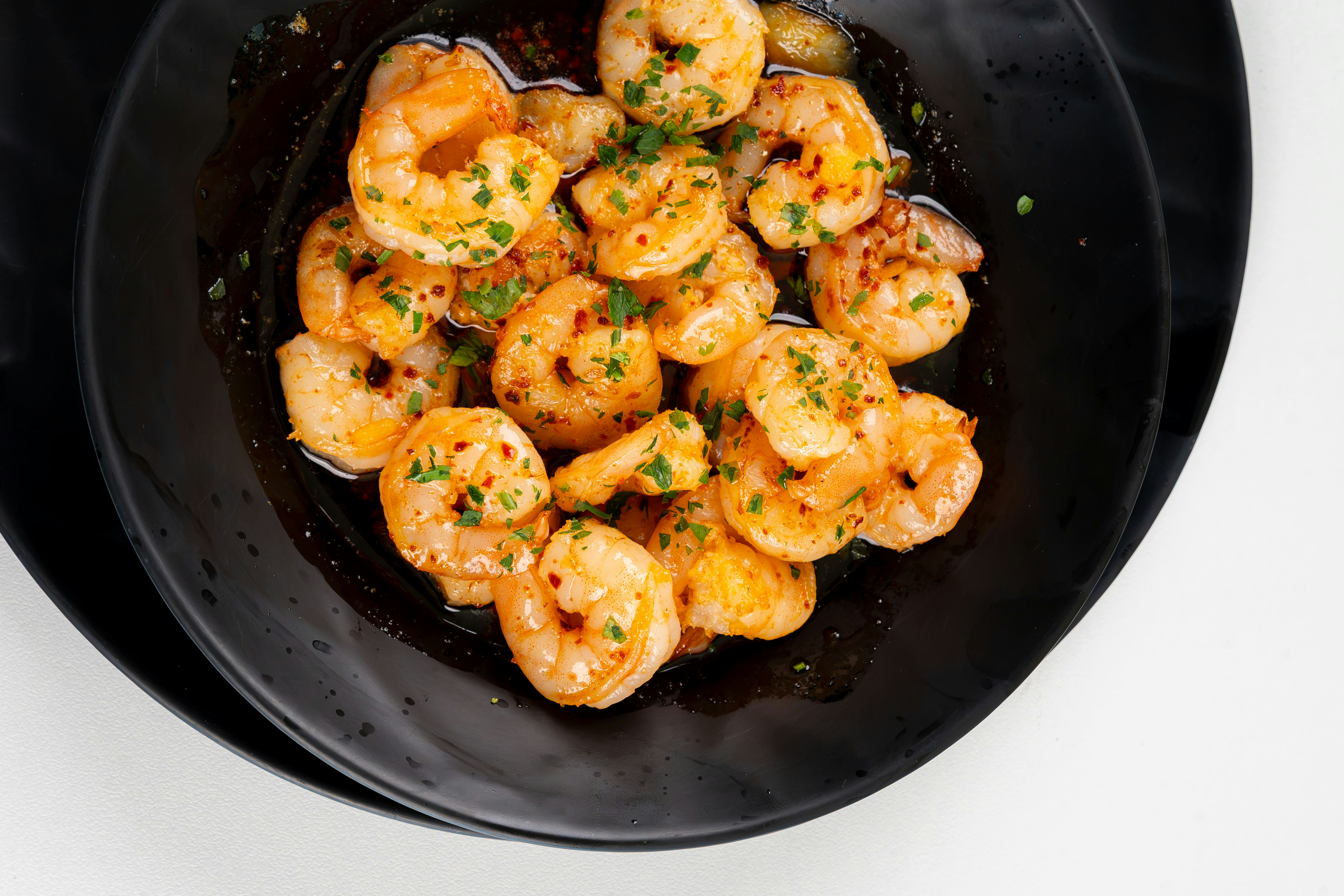 Cooked shrimp with herbs and chili flakes in a black bowl