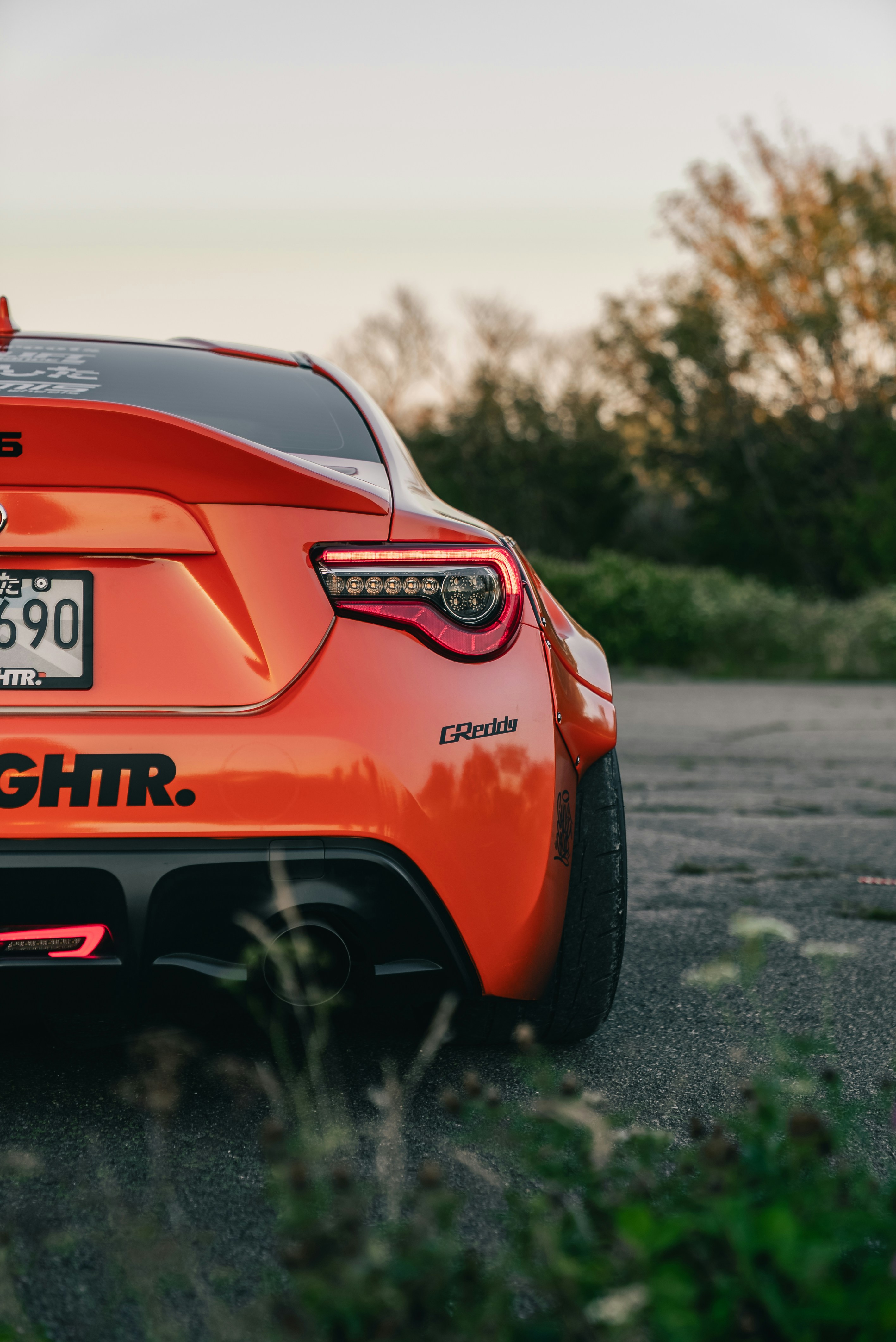 Rear view of an orange sports car with a wide body kit on asphalt