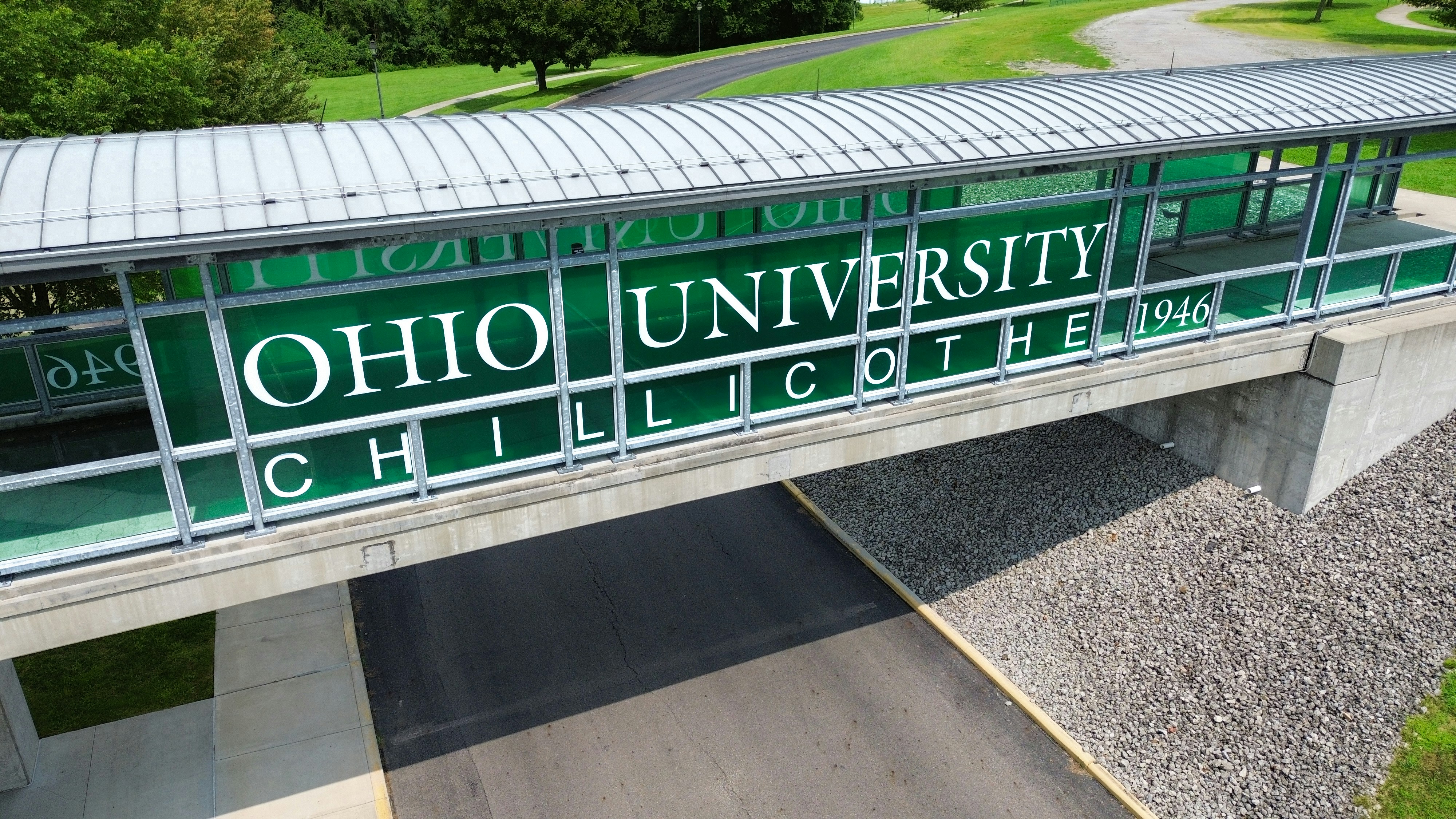 An enclosed pedestrian bridge with green signage reading Ohio University Chillicothe over a road
