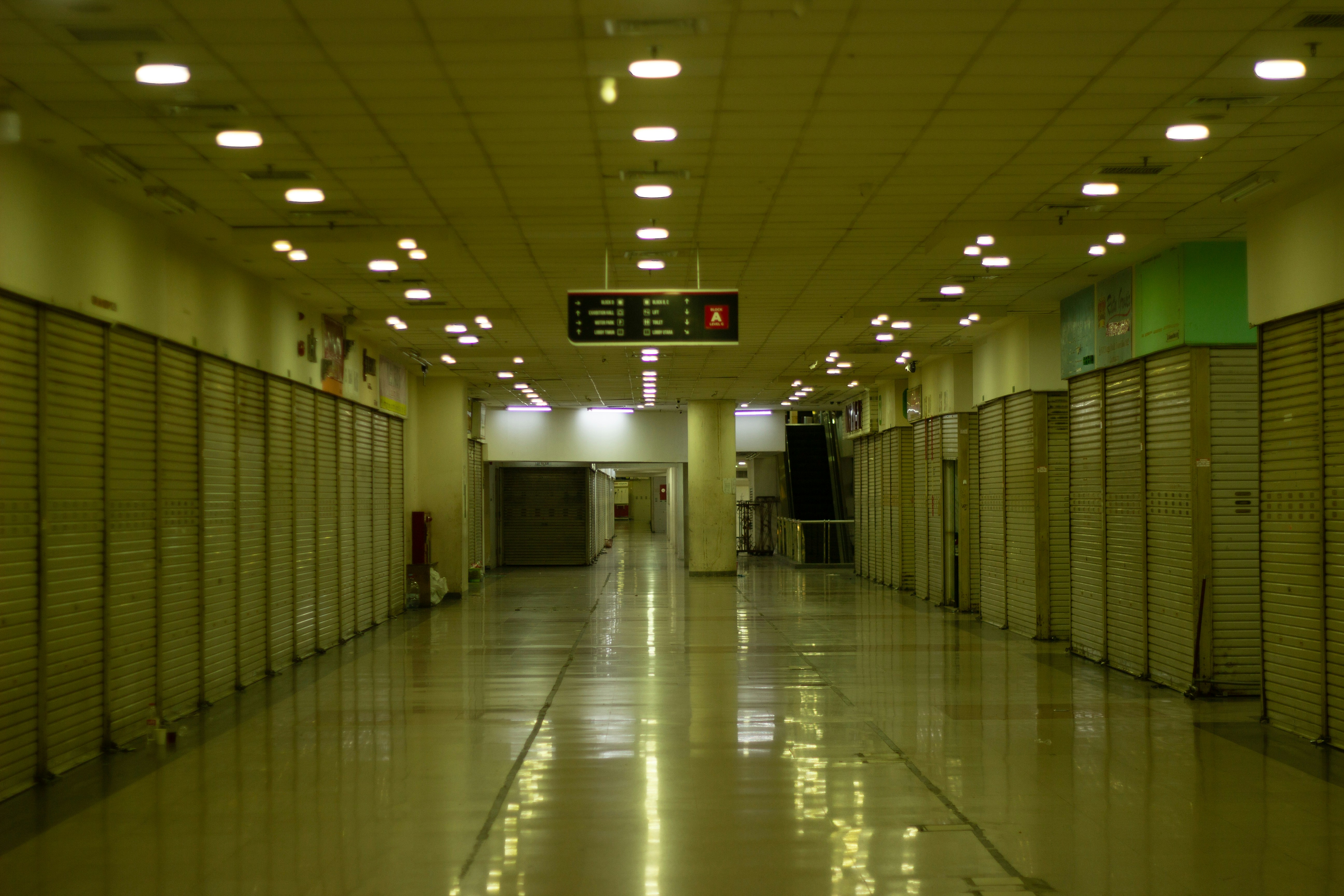 A long empty corridor in a shopping mall with closed metal shutters