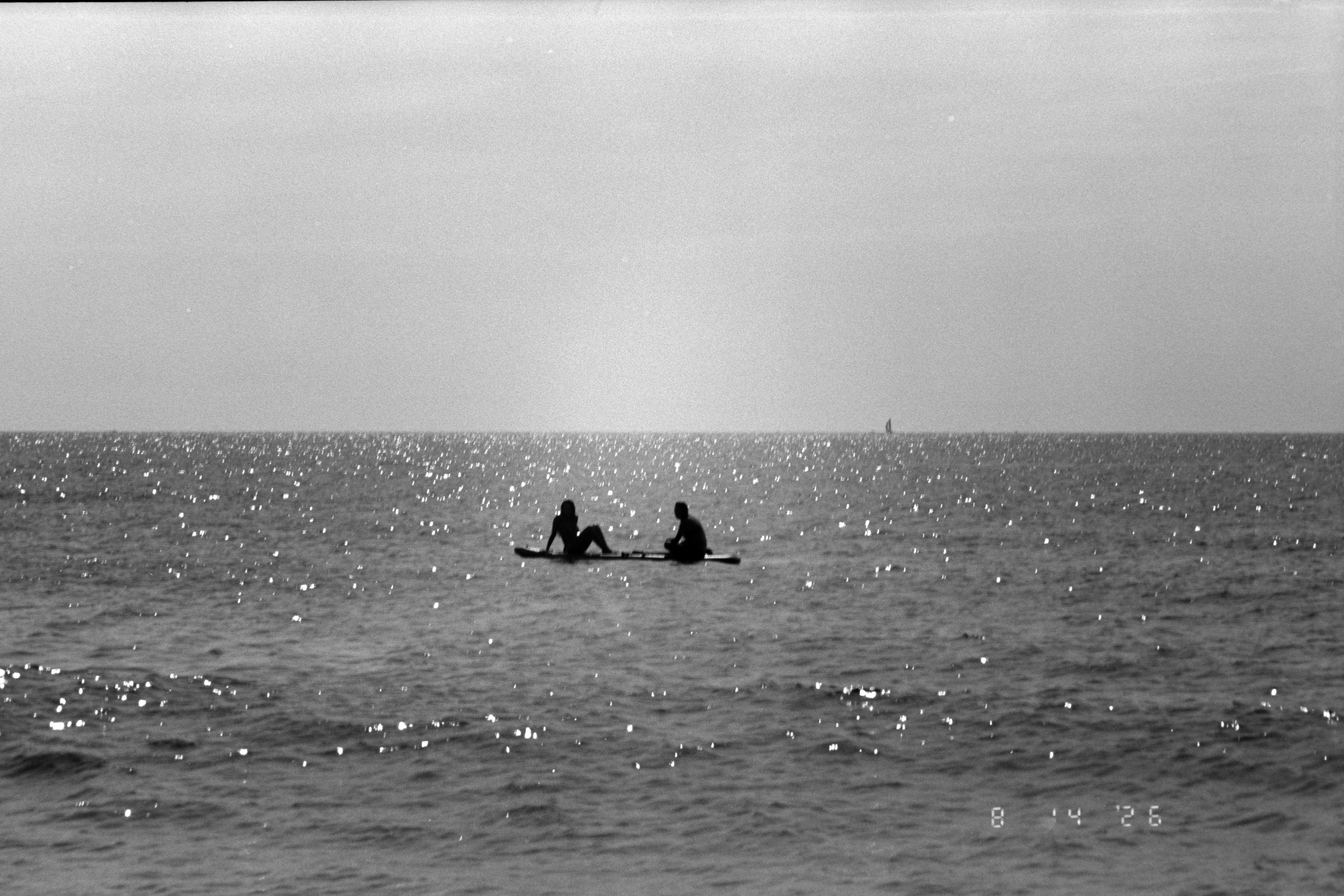 Dos personas en una tabla de paddle en medio de un mar brillante