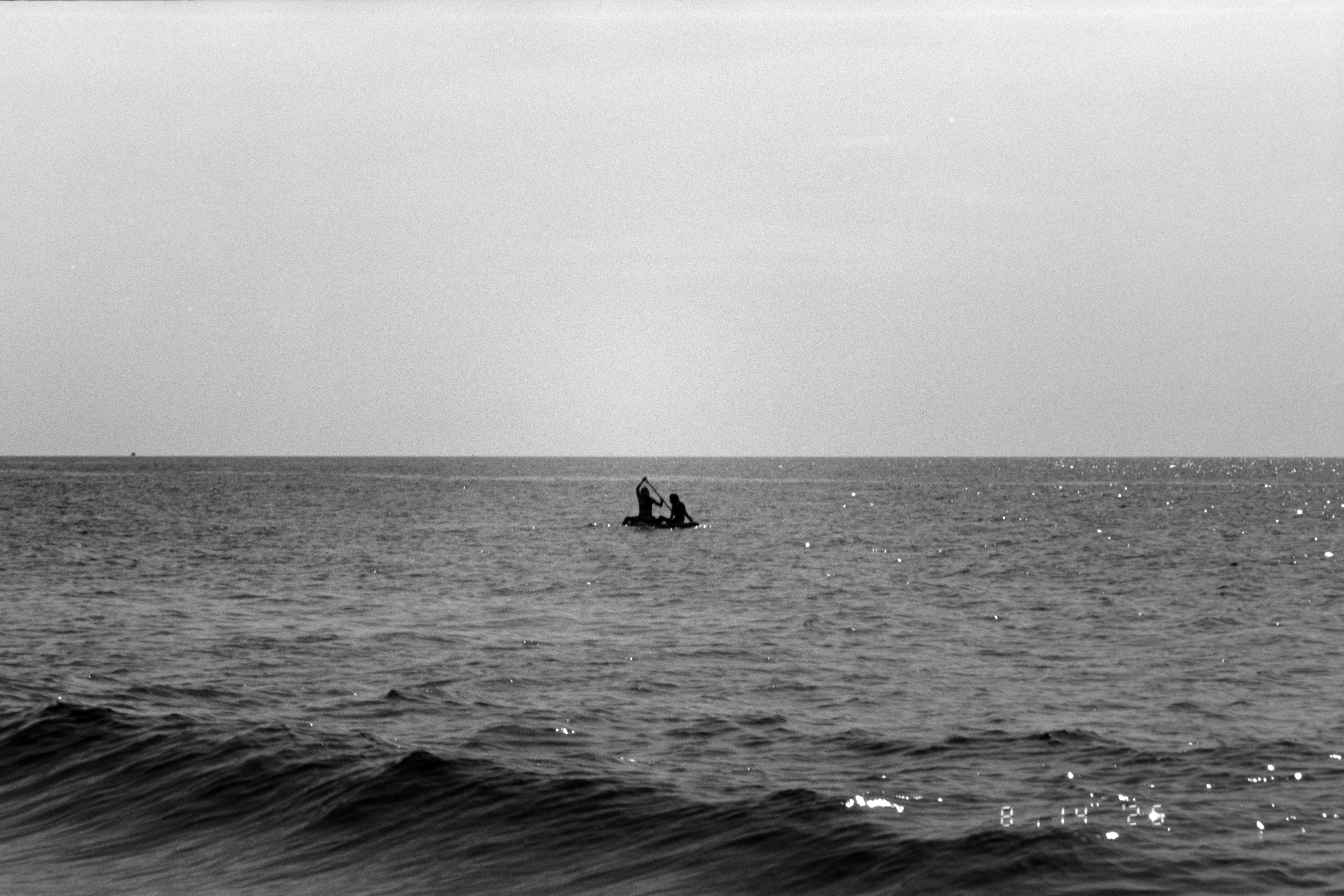 Dos personas en una pequeña barca remando en mar abierto