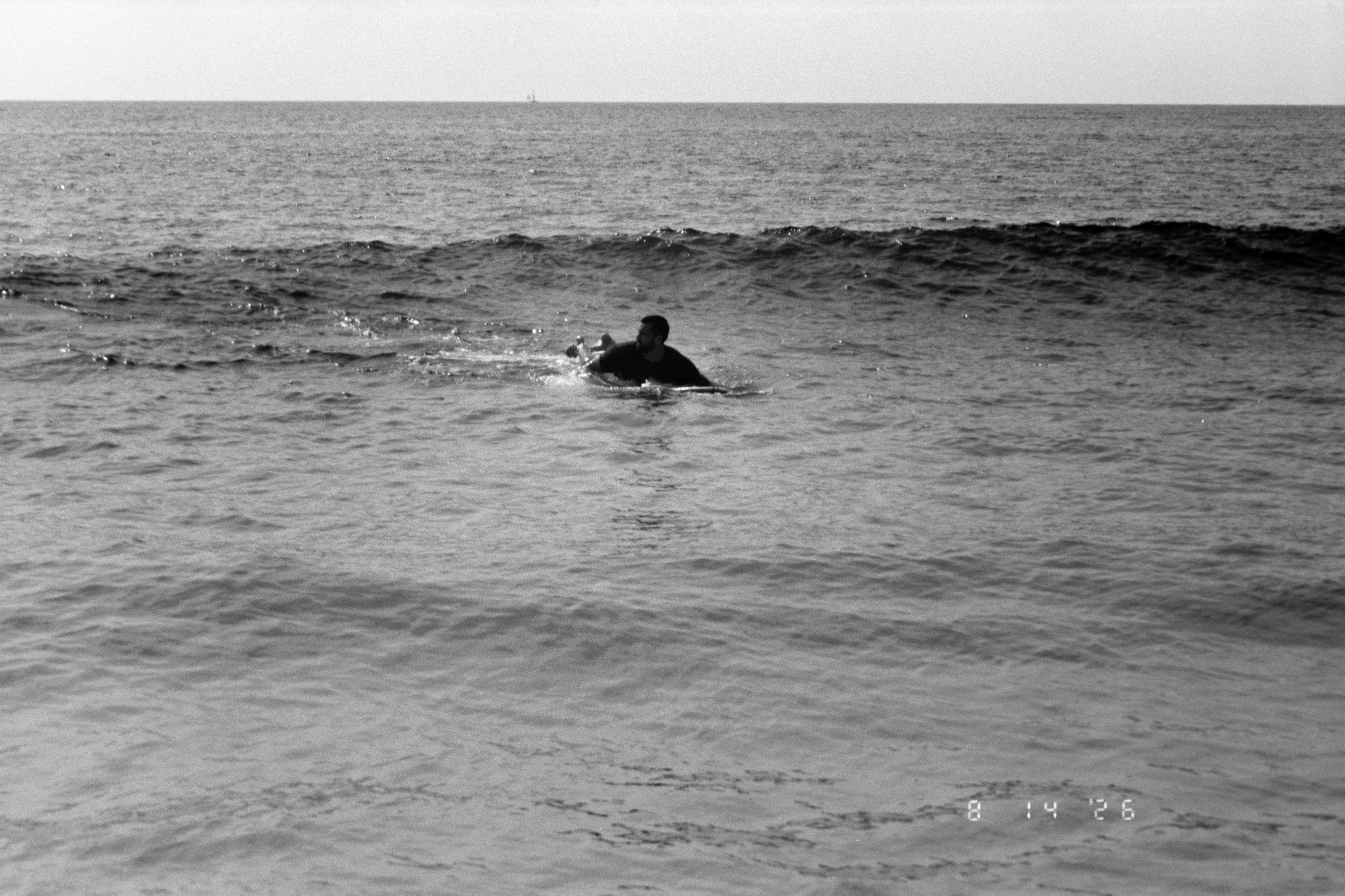Una persona remando sobre una tabla de surf en el océano con una pequeña ola