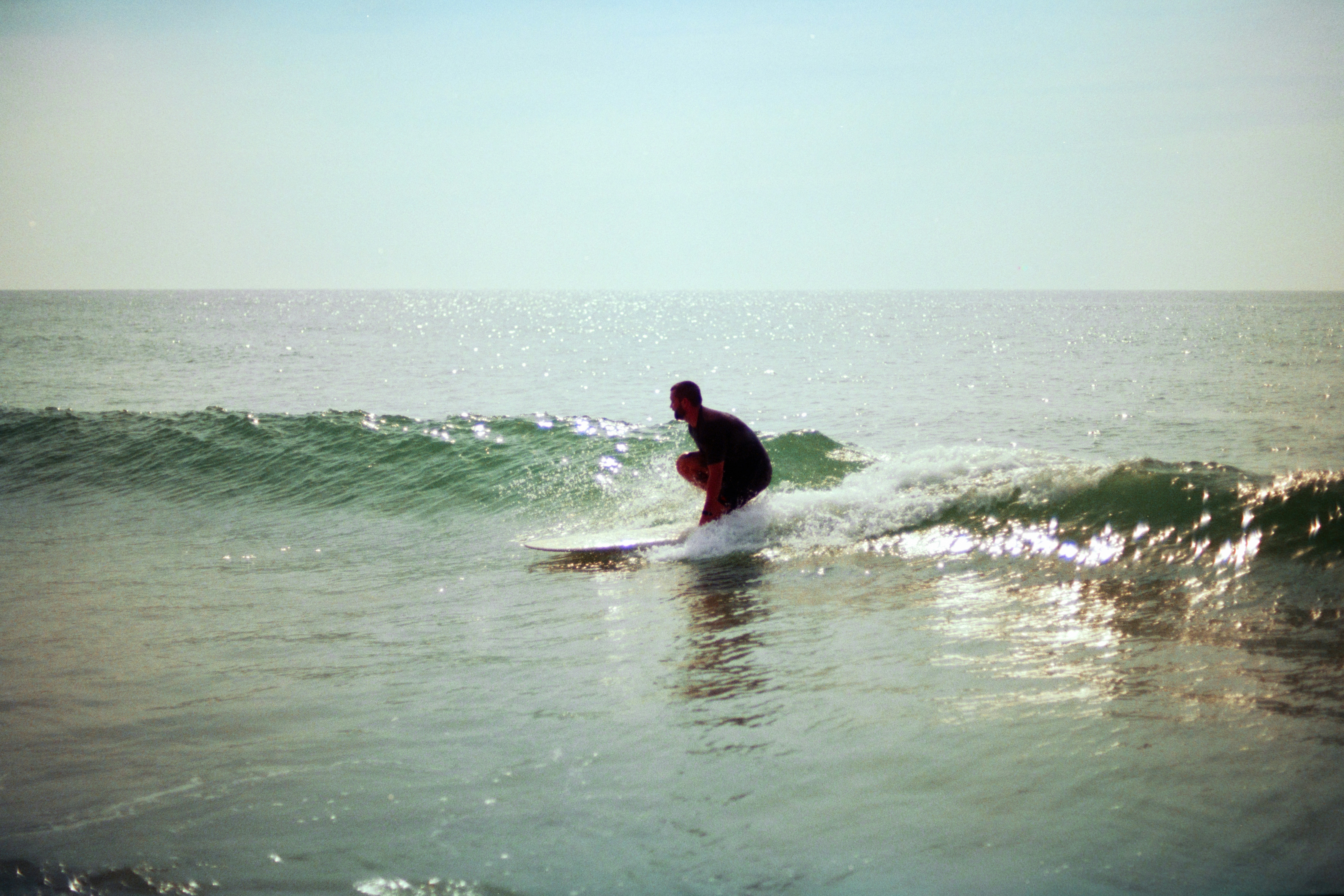 Una persona surfeando una pequeña ola en el océano bajo un sol intenso
