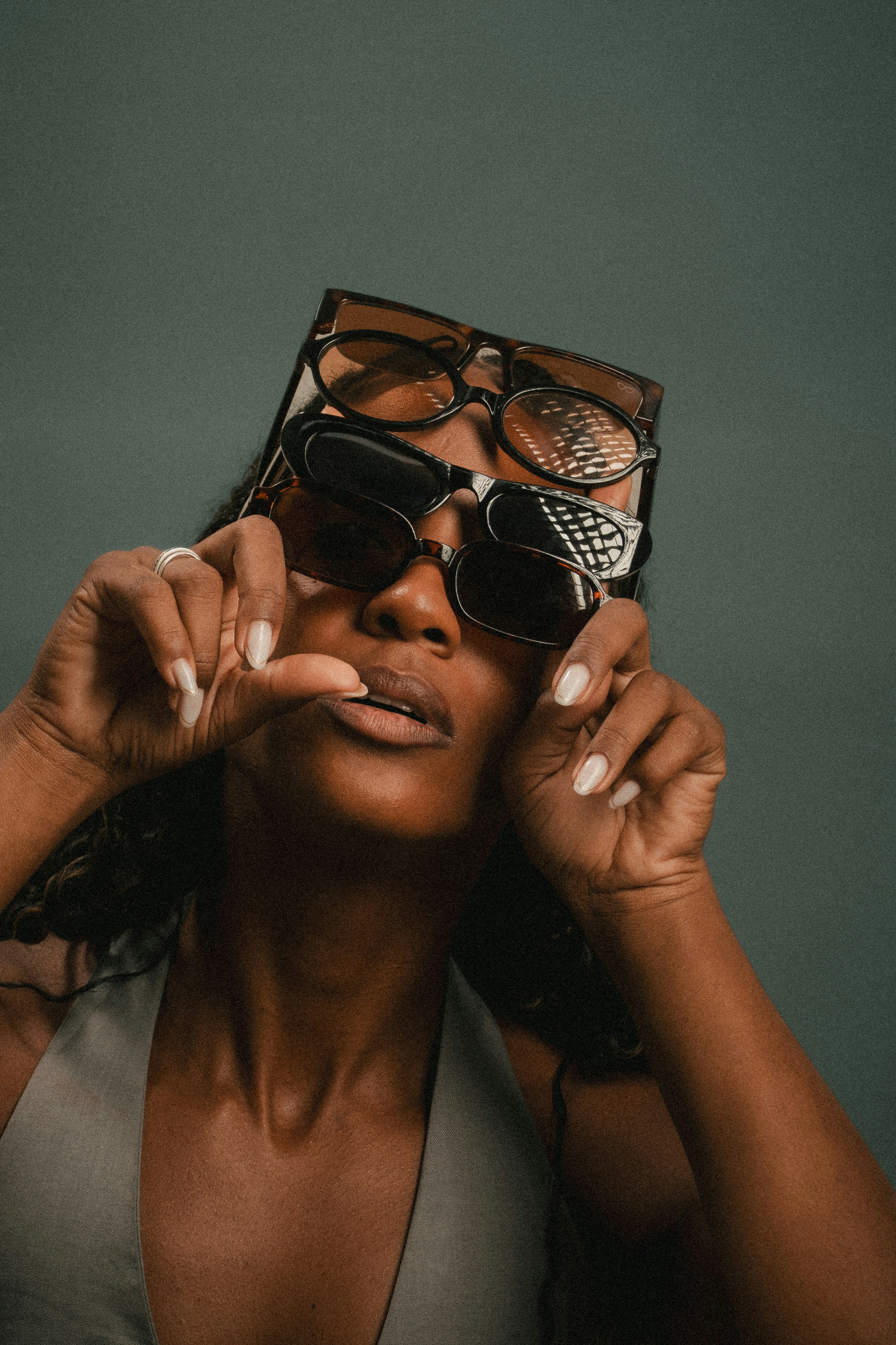 A person holding three pairs of stacked sunglasses in front of their face