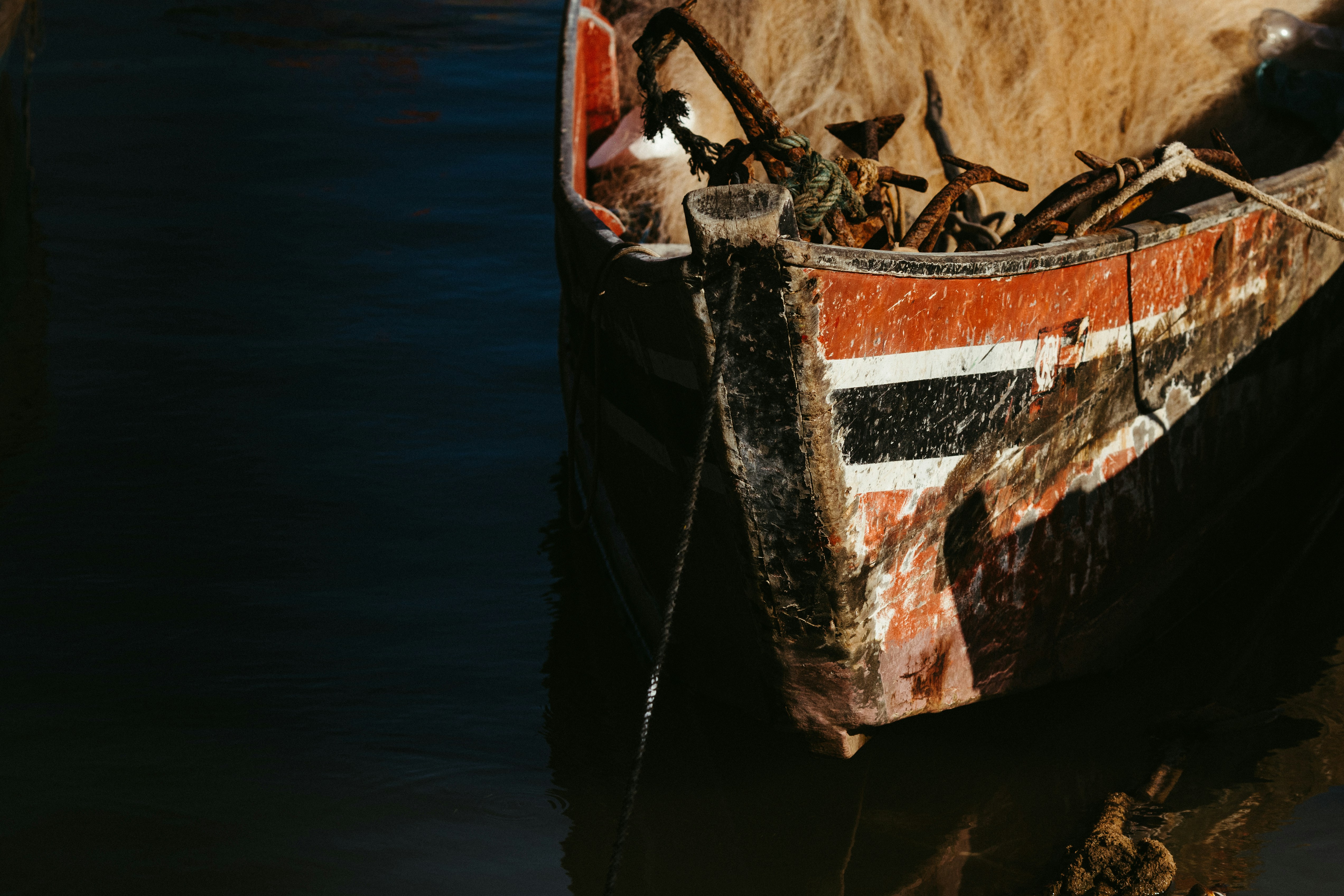 La proa de un barco pesquero de madera desgastada con pintura roja y negra