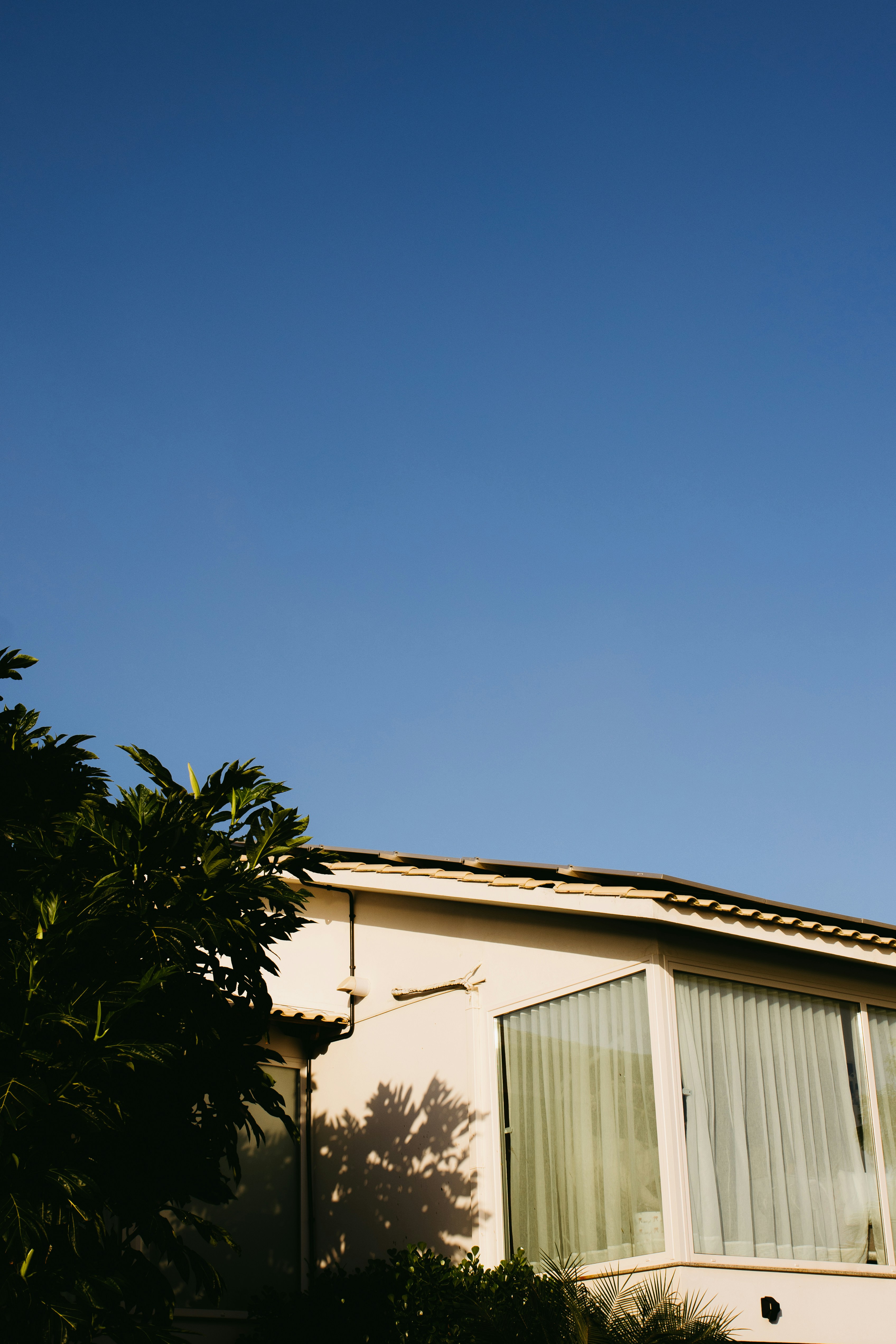 Un exterior de casa con grandes ventanales bajo un cielo azul claro