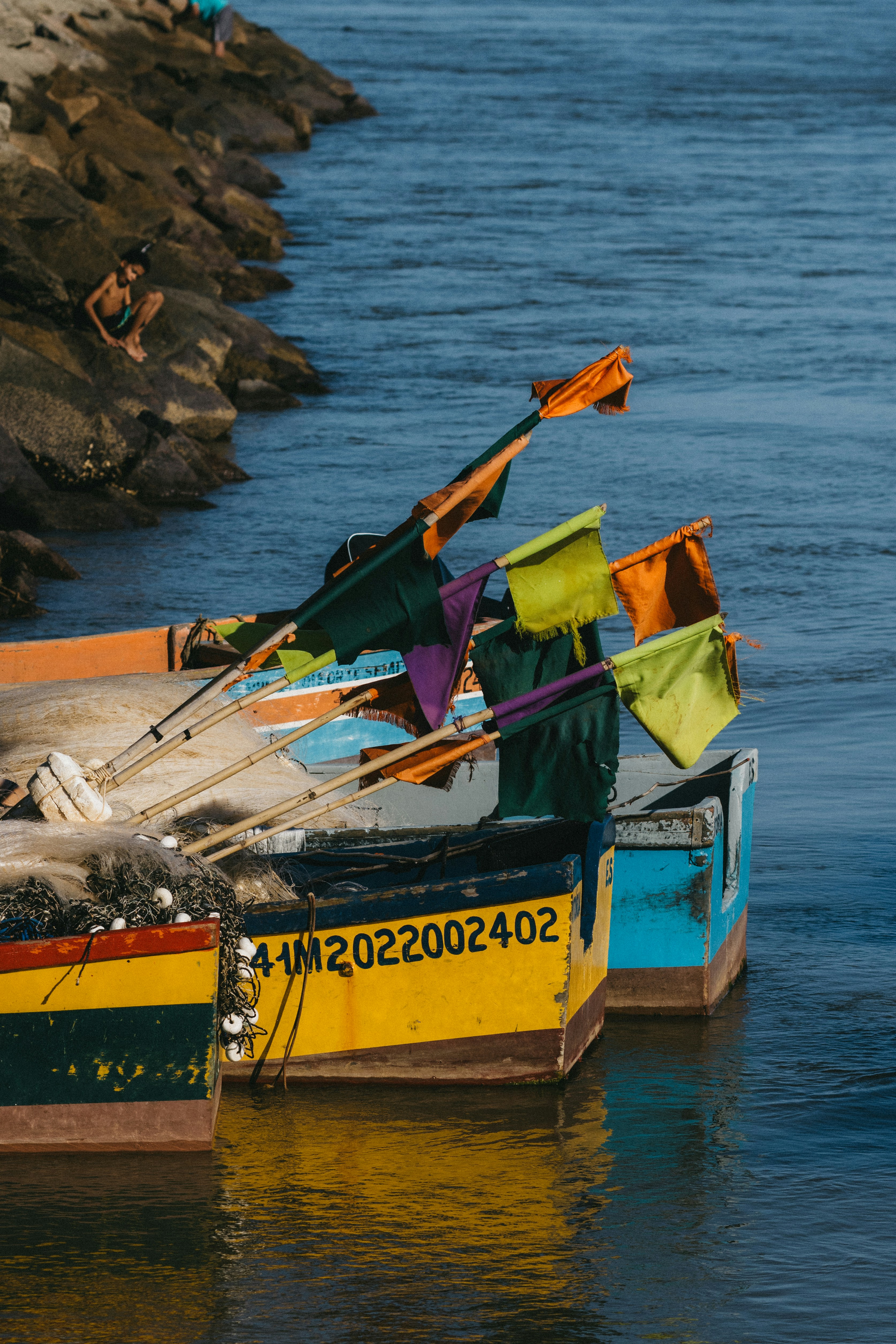 Coloridos barcos de pesca con banderas y redes amarrados en una orilla rocosa del río