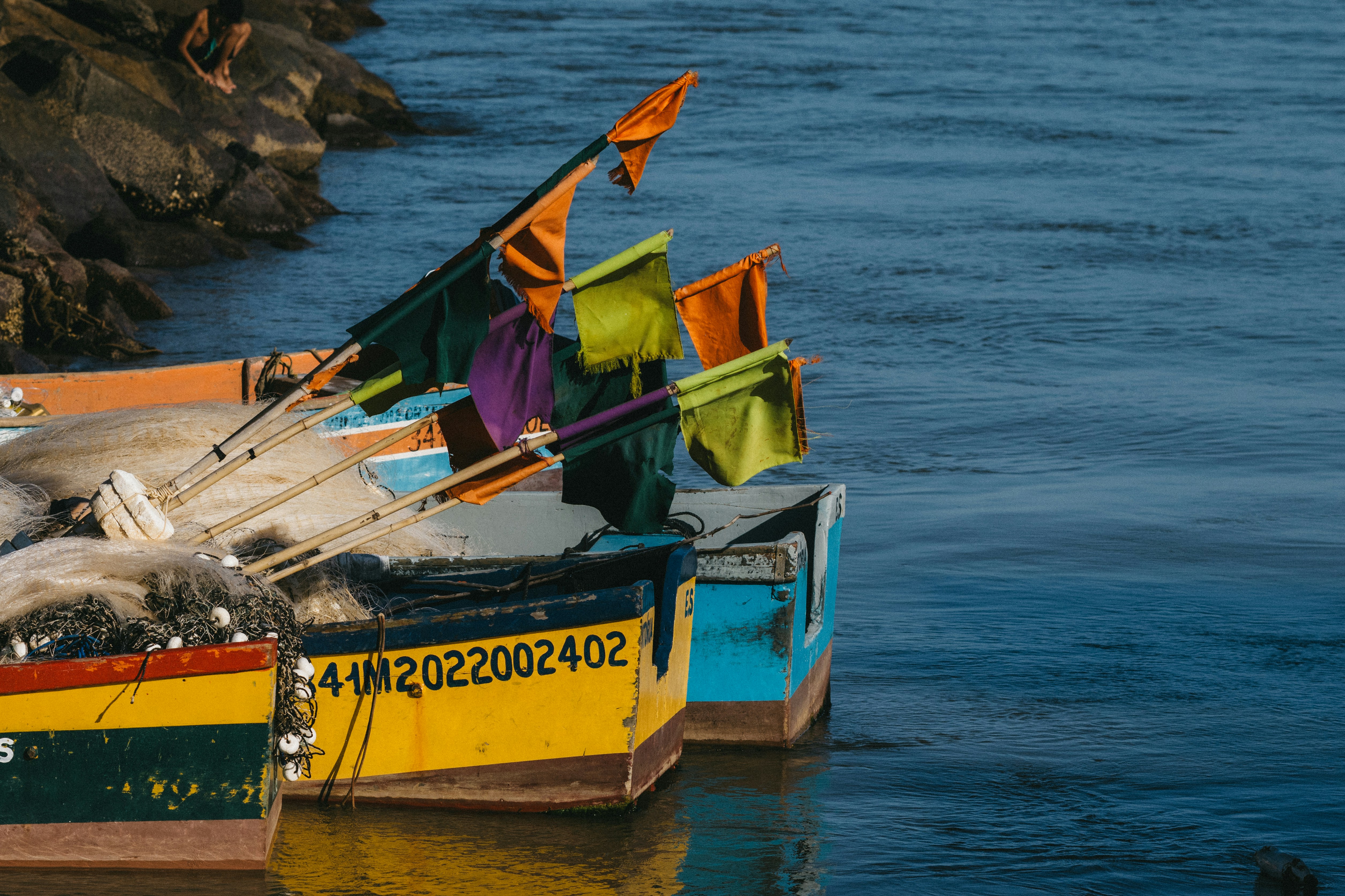 Coloridos barcos de pesca con redes y pequeñas banderas amarrados en una costa rocosa