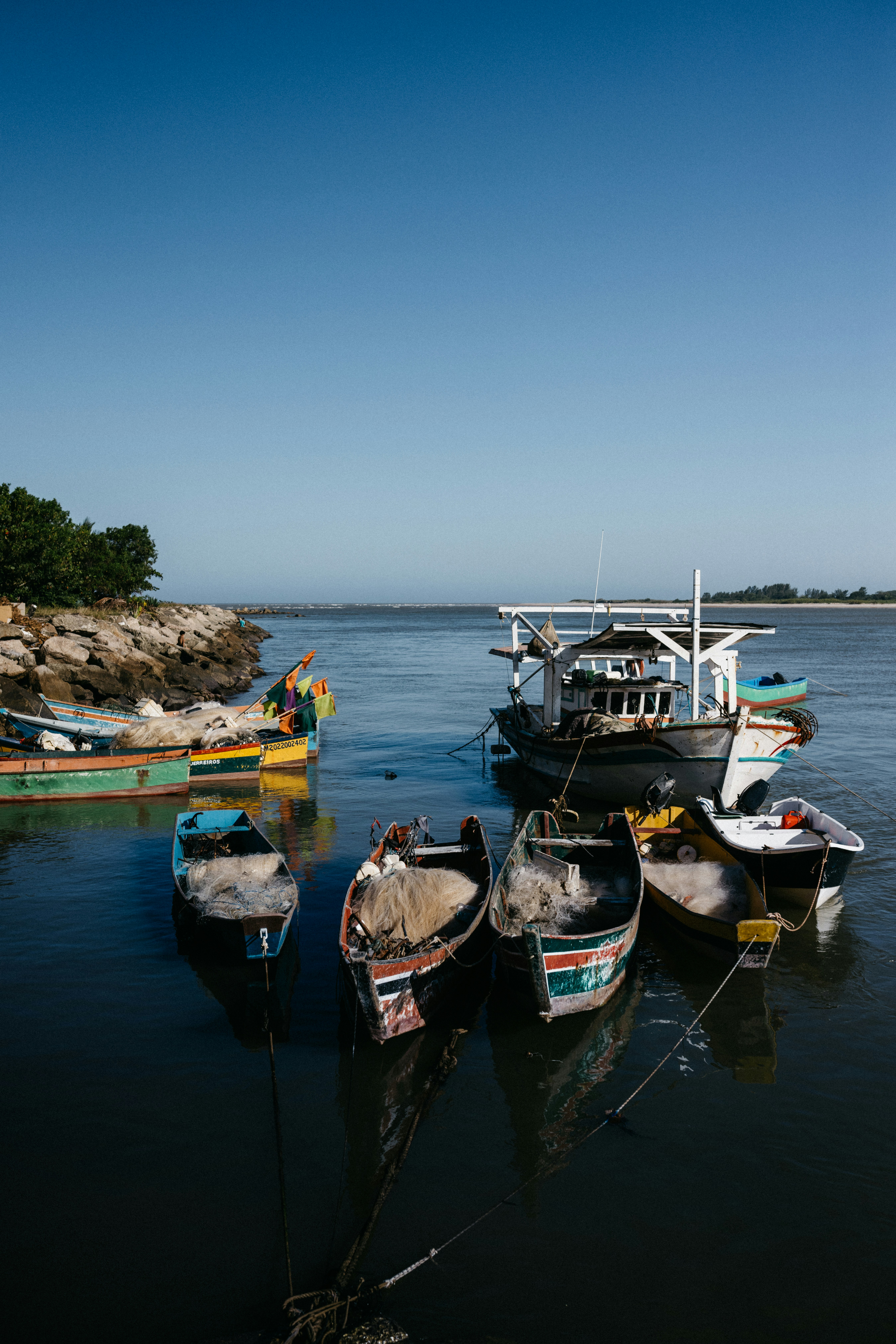 Pequeños barcos de pesca coloridos con redes amarrados en un tranquilo puerto costero
