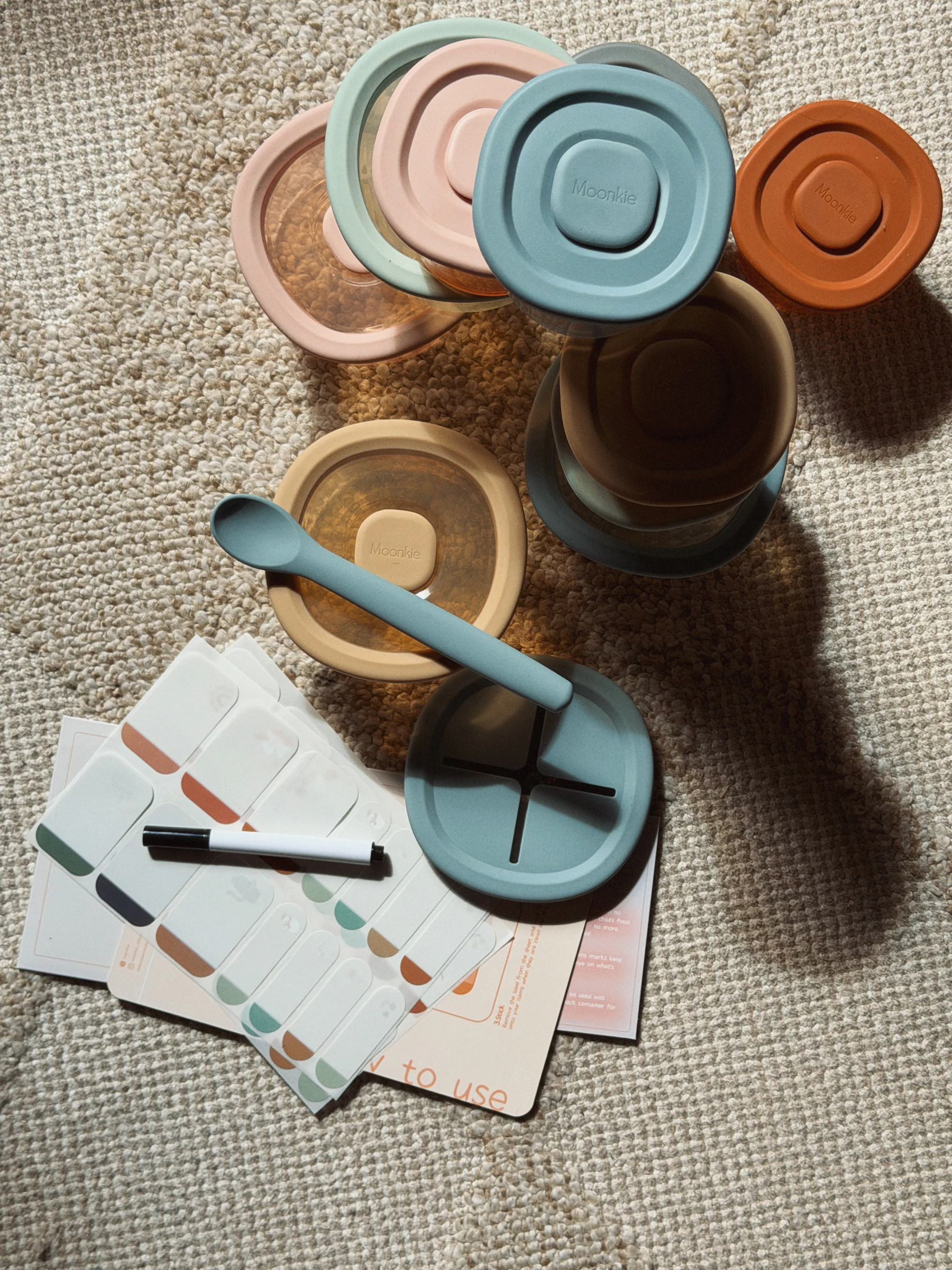 Pastel lidded baby food containers with a silicone spoon, write-on labels and a marker