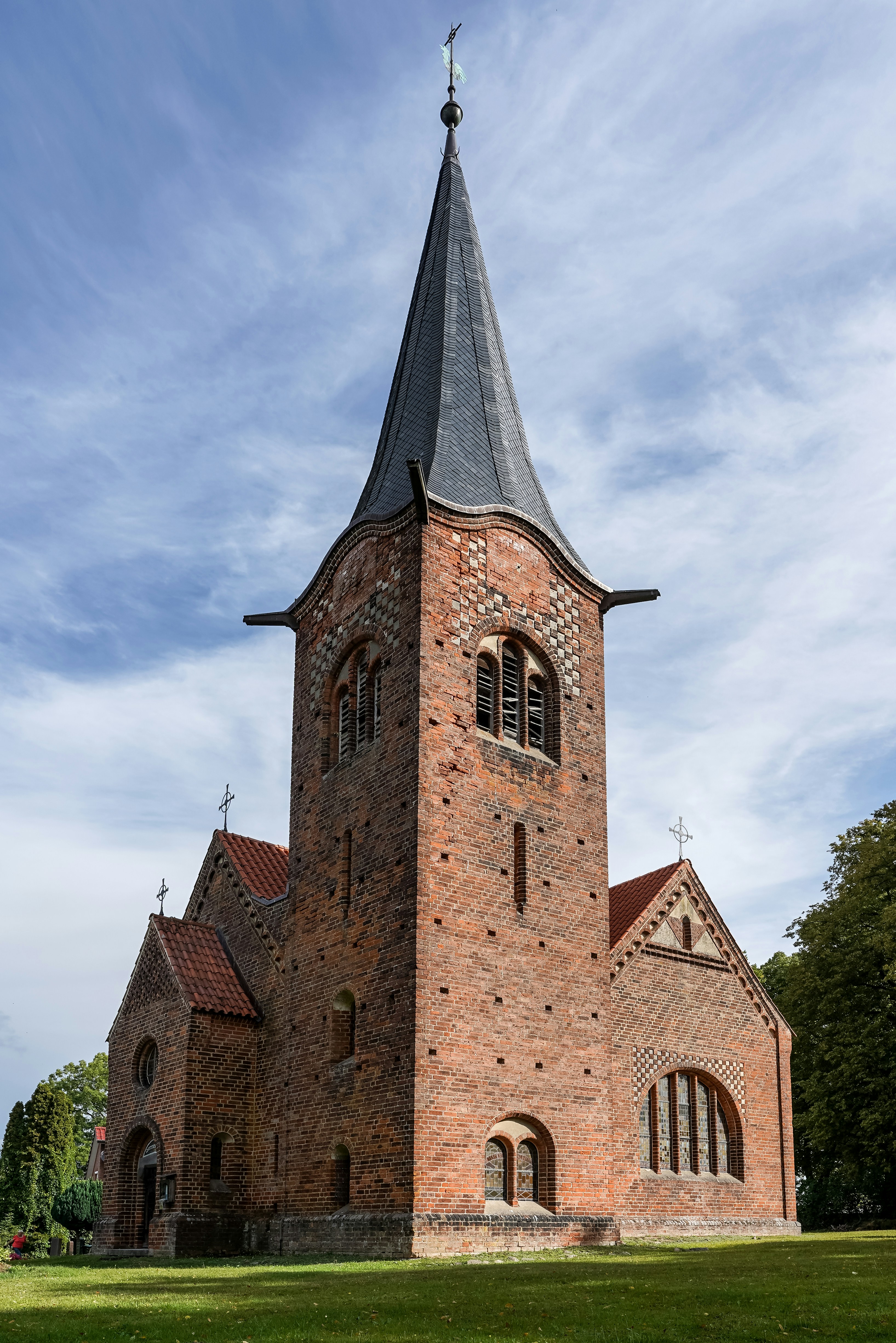 A red brick church with a tall steeple under a blue sky