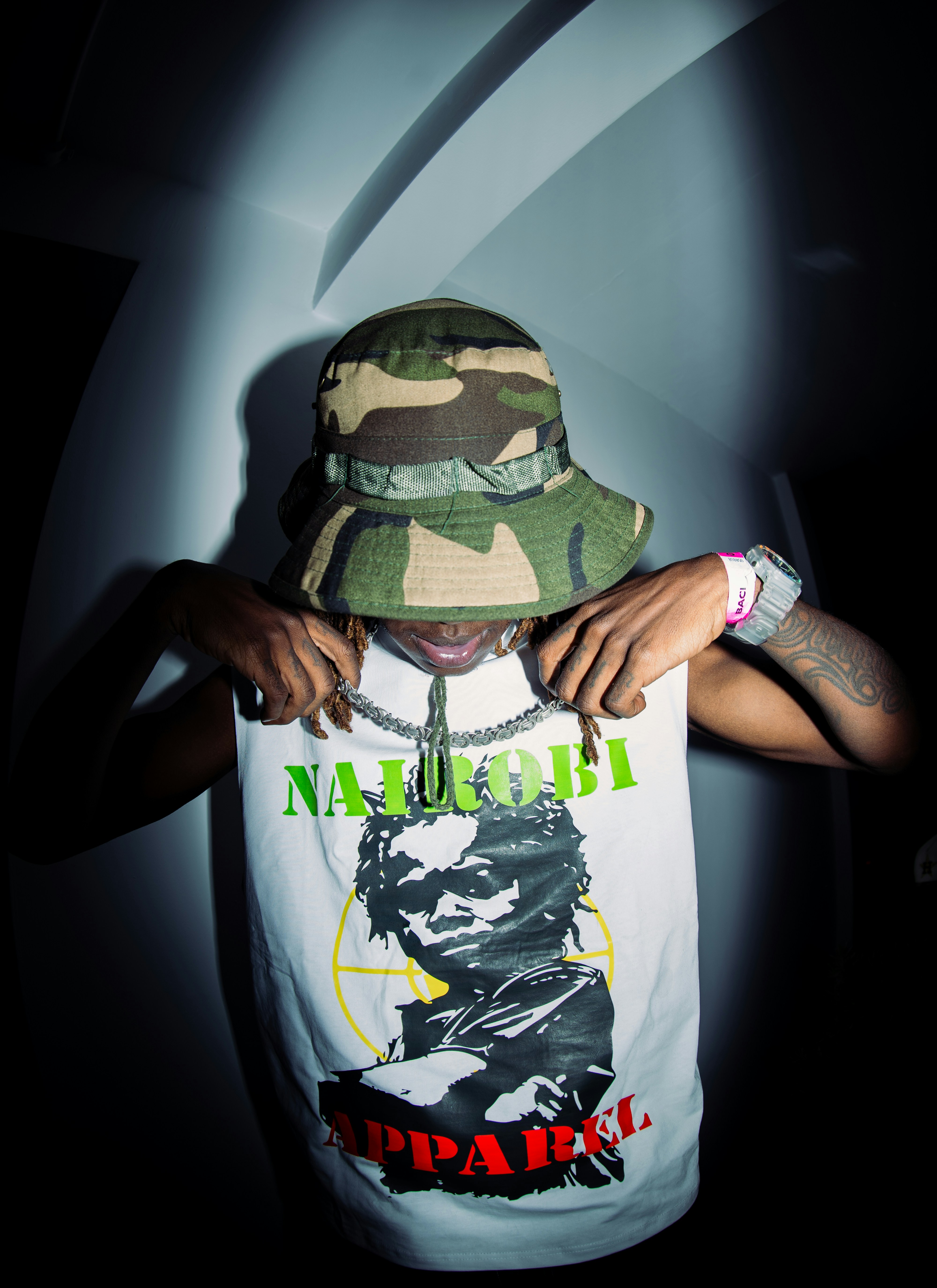 A person in a camouflage bucket hat and white graphic tank top