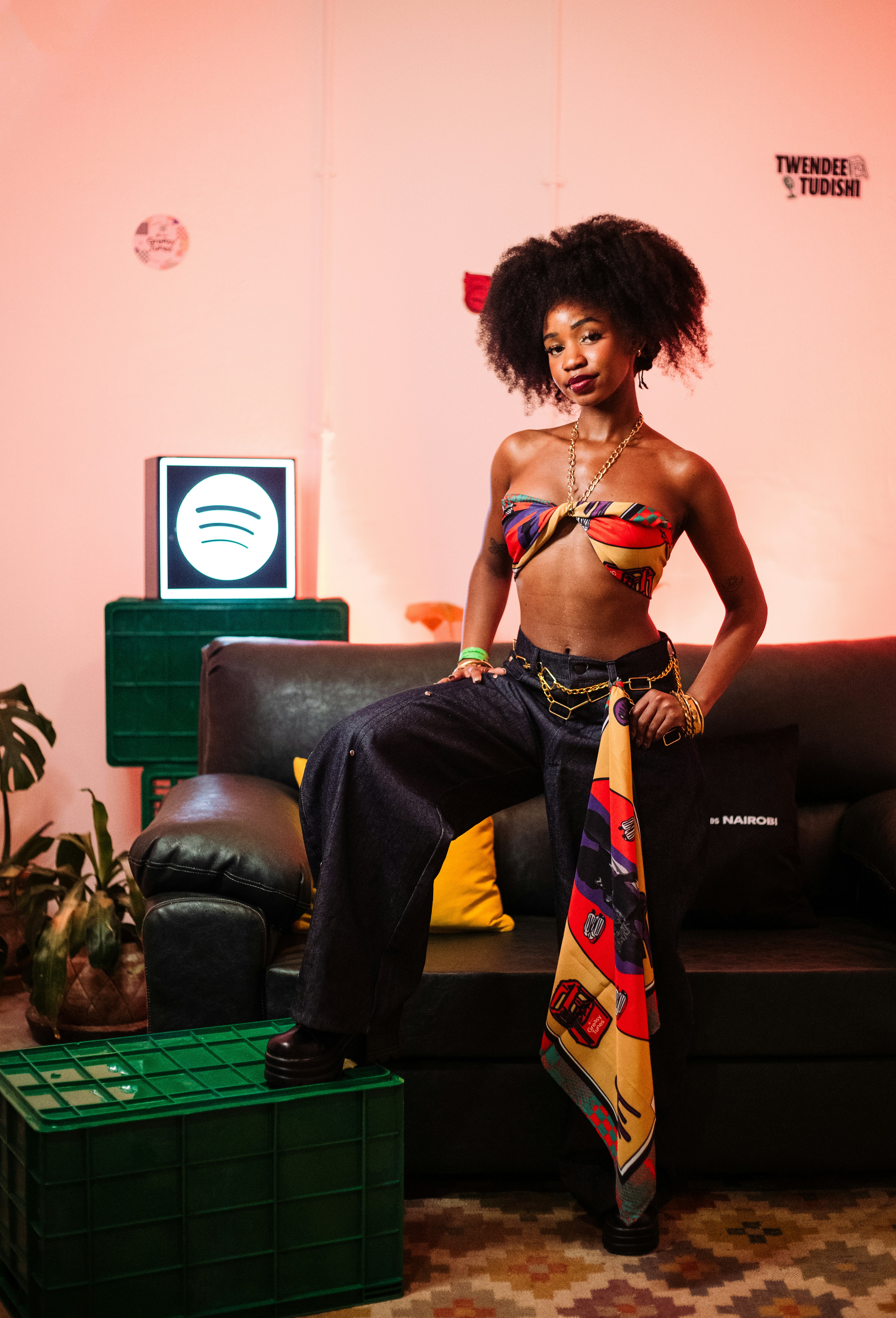 A woman with an afro wearing a patterned scarf top and dark jeans