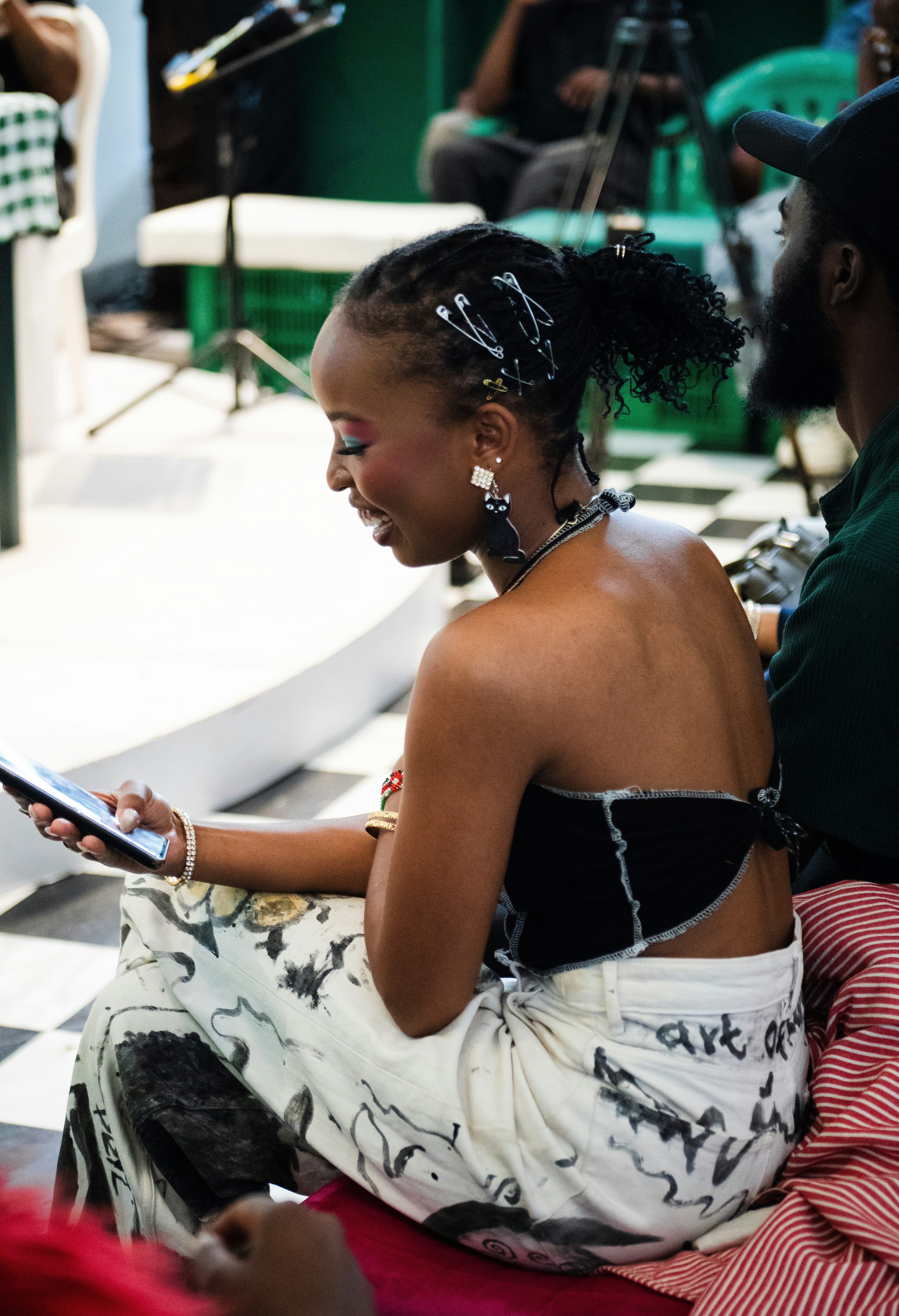 A woman with safety pins in her hair looking at a smartphone