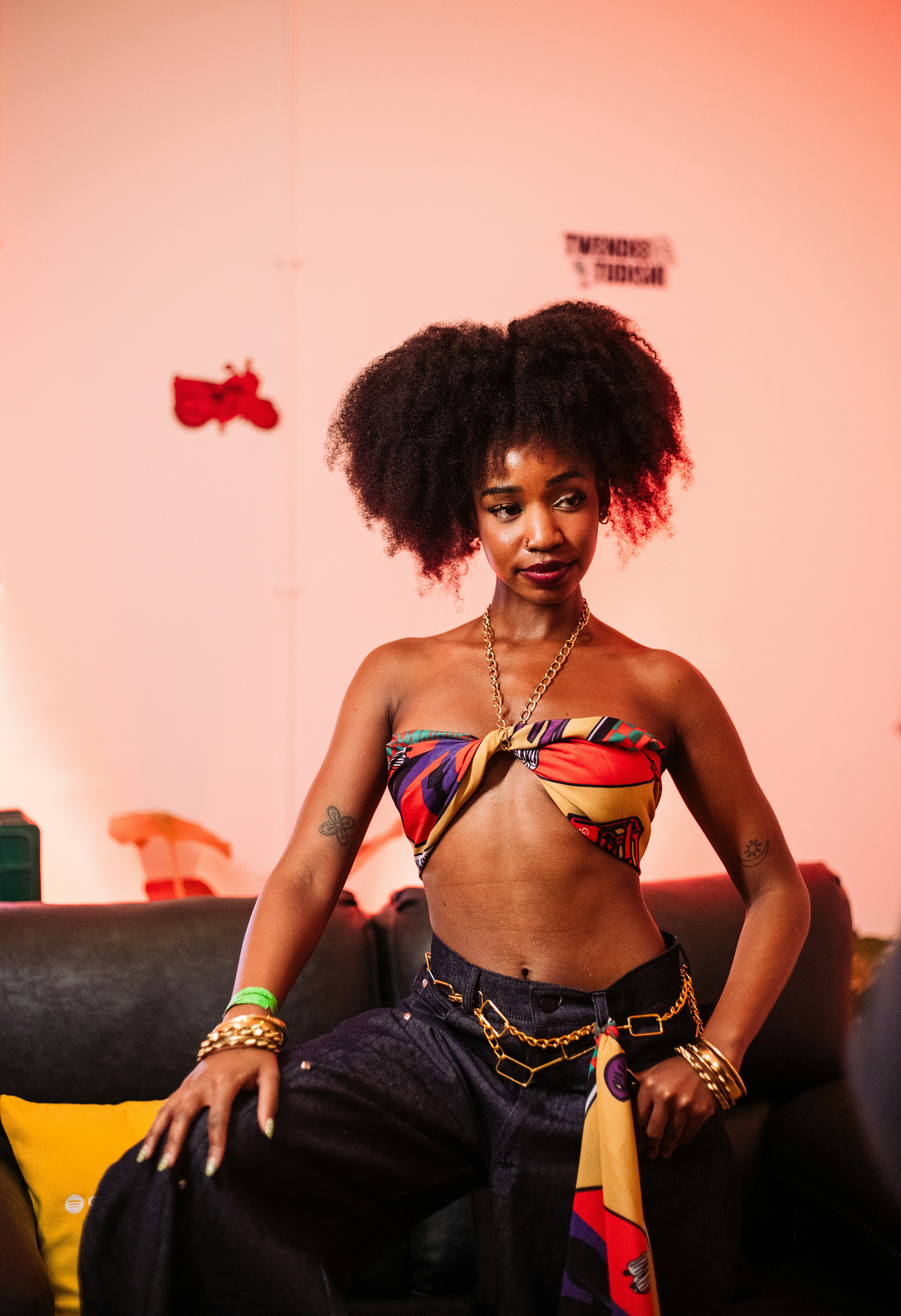 A woman with an afro wearing a colorful scarf top and dark jeans