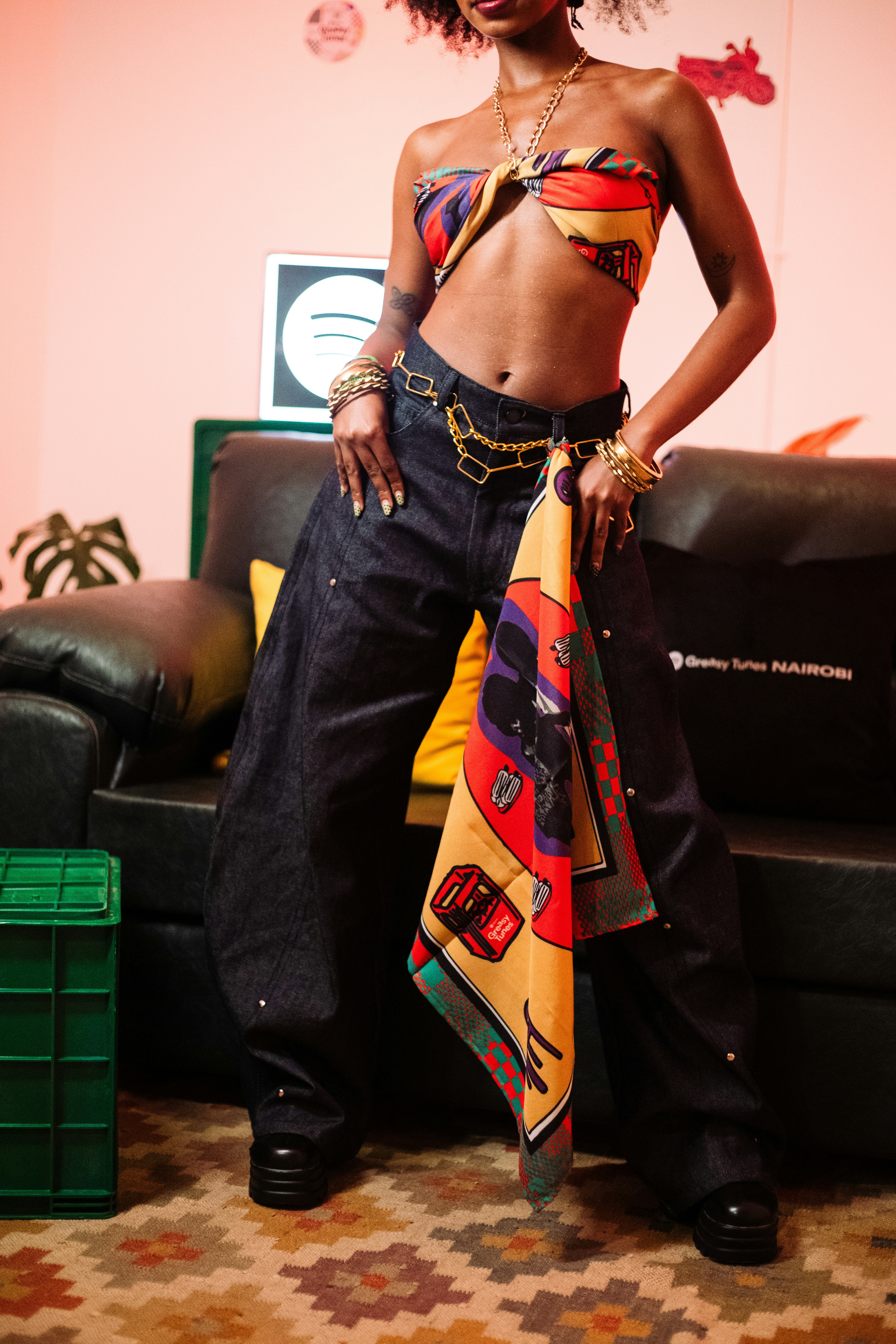A person wearing a colorful scarf top and dark denim jeans in a room