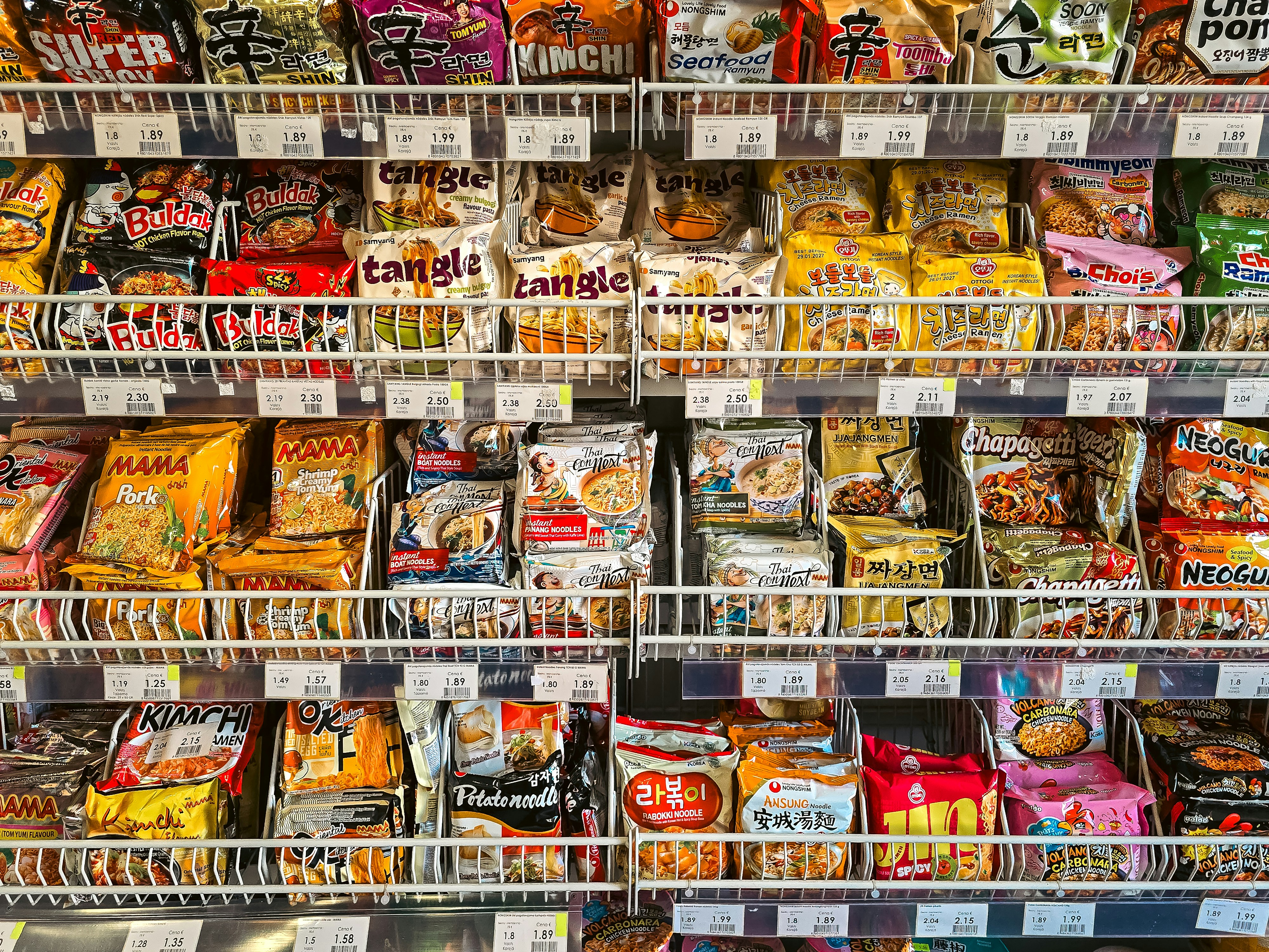 Rows of various instant noodle packages on shelves in a grocery store