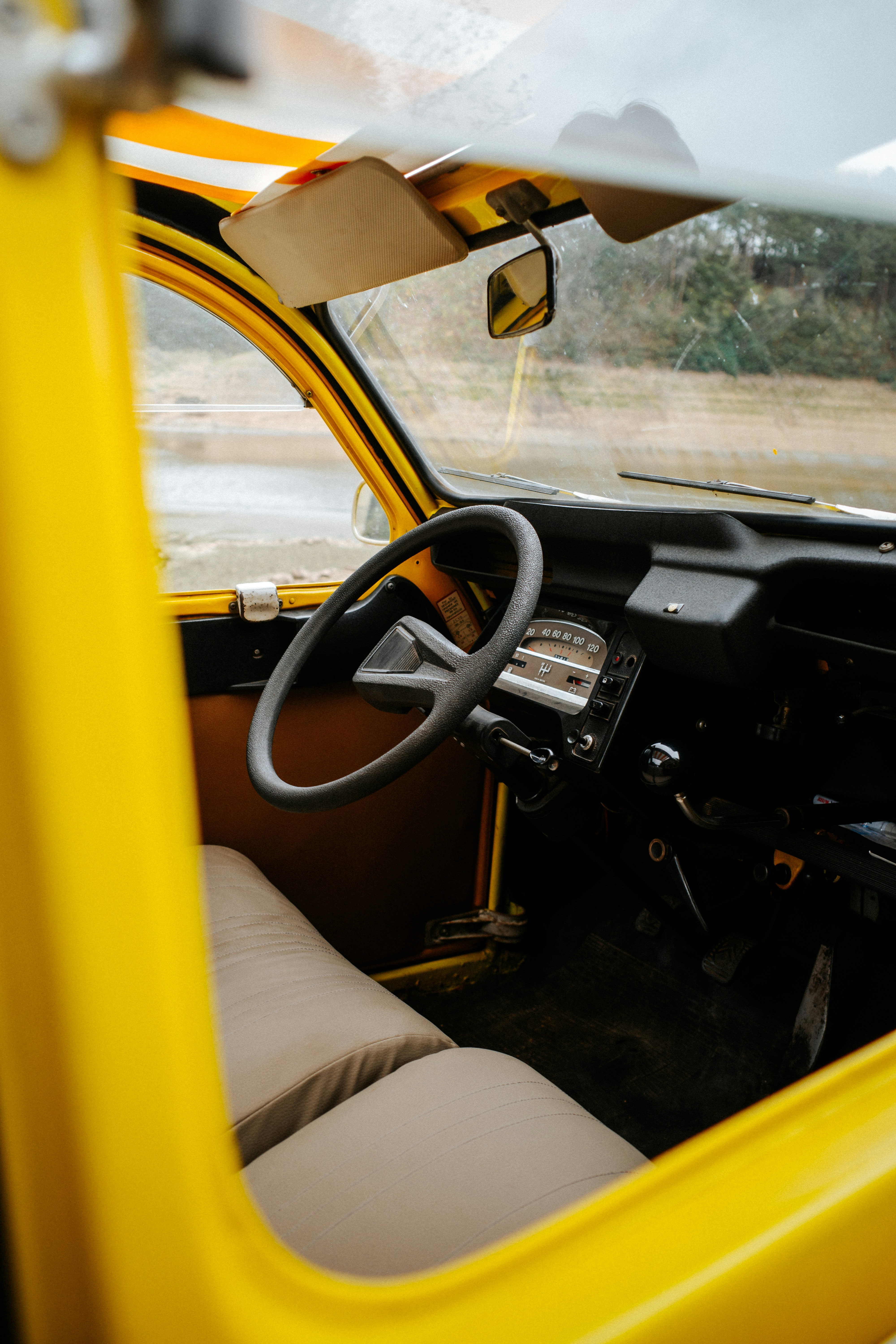 Interni di una Citroën 2CV gialla con sedili beige e volante nero