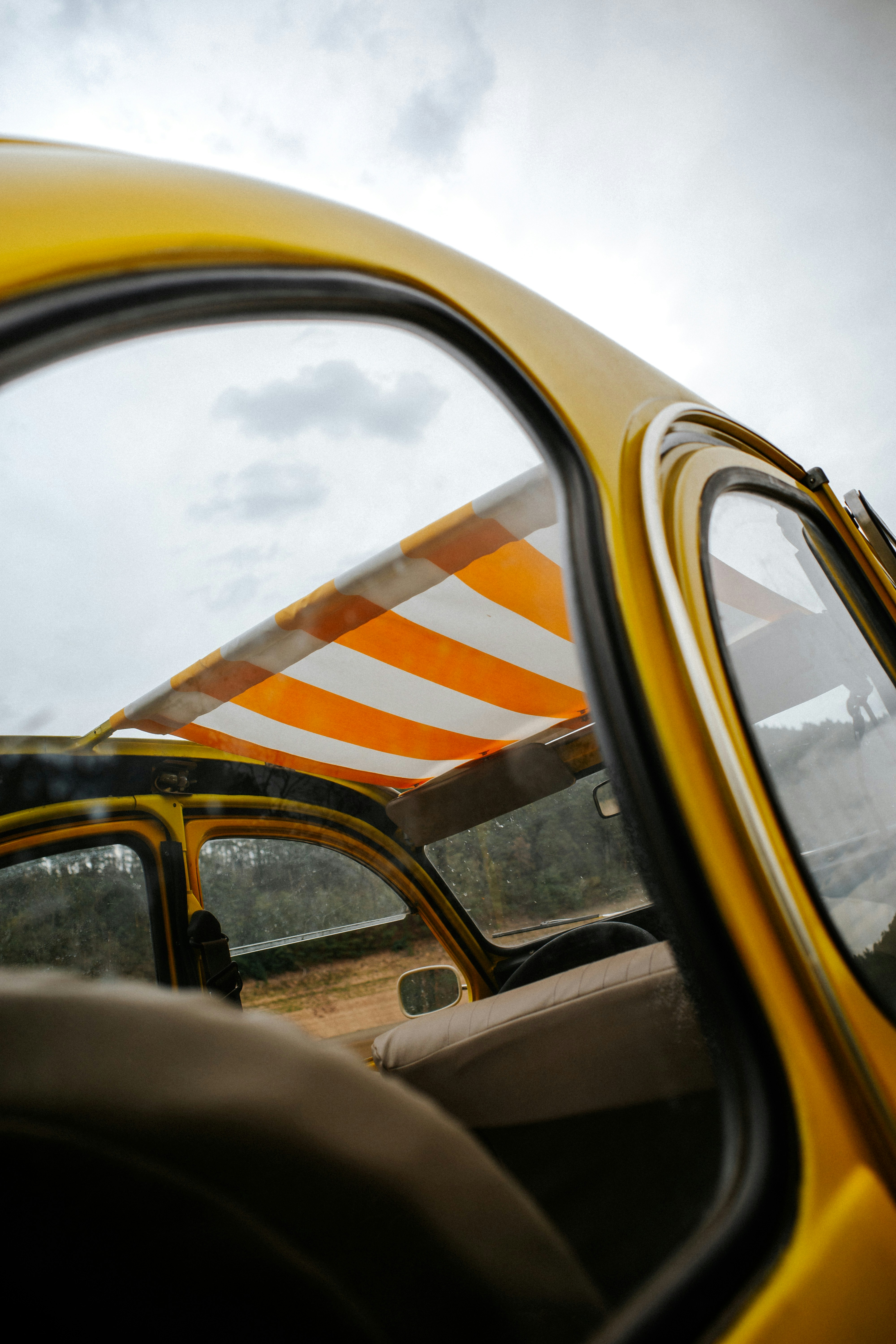Interno di un'auto gialla con tetto aperto a righe arancioni e bianche