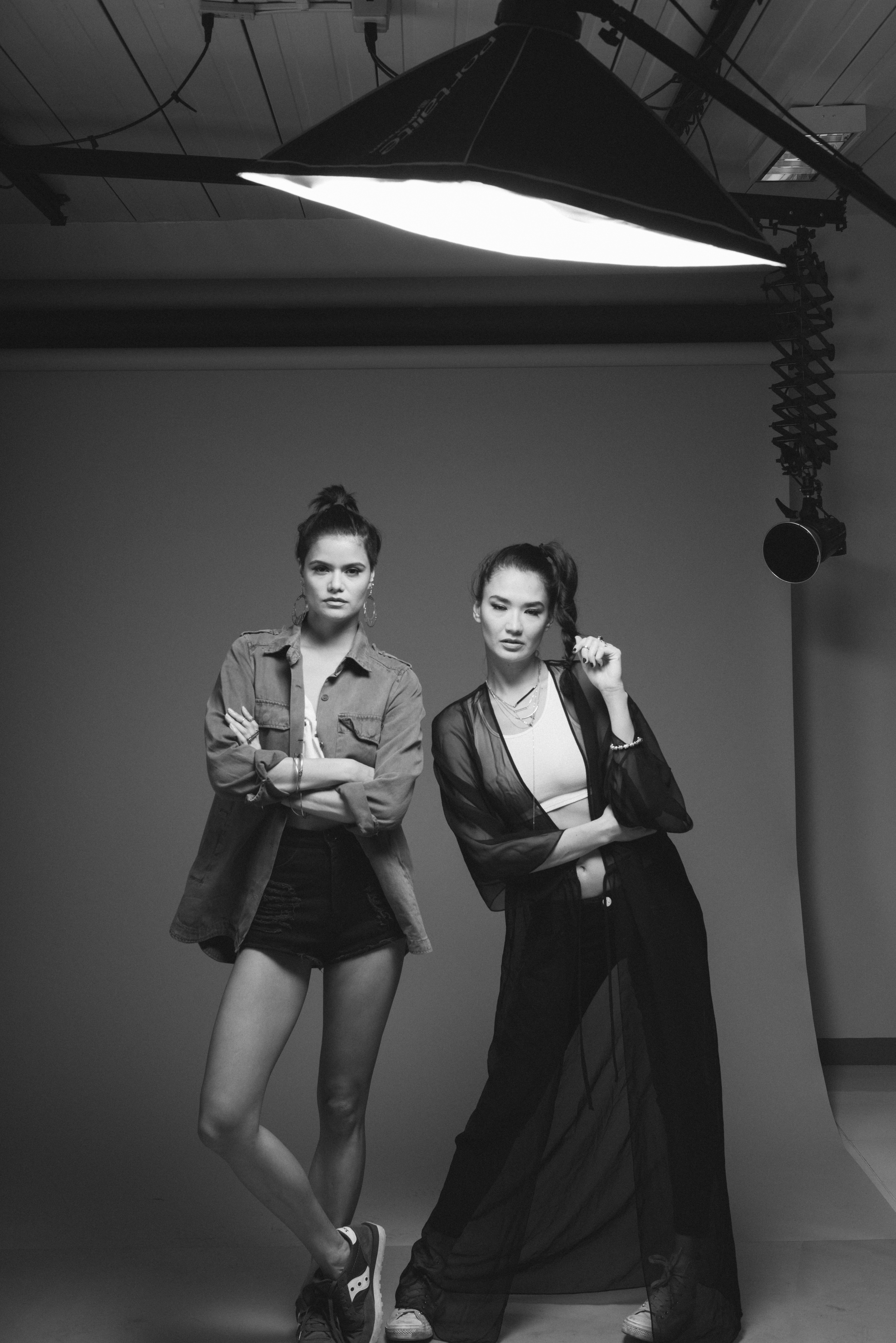 Two women posing in a studio with a large overhead light fixture