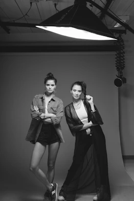 Two women posing in a studio with a large overhead light fixture