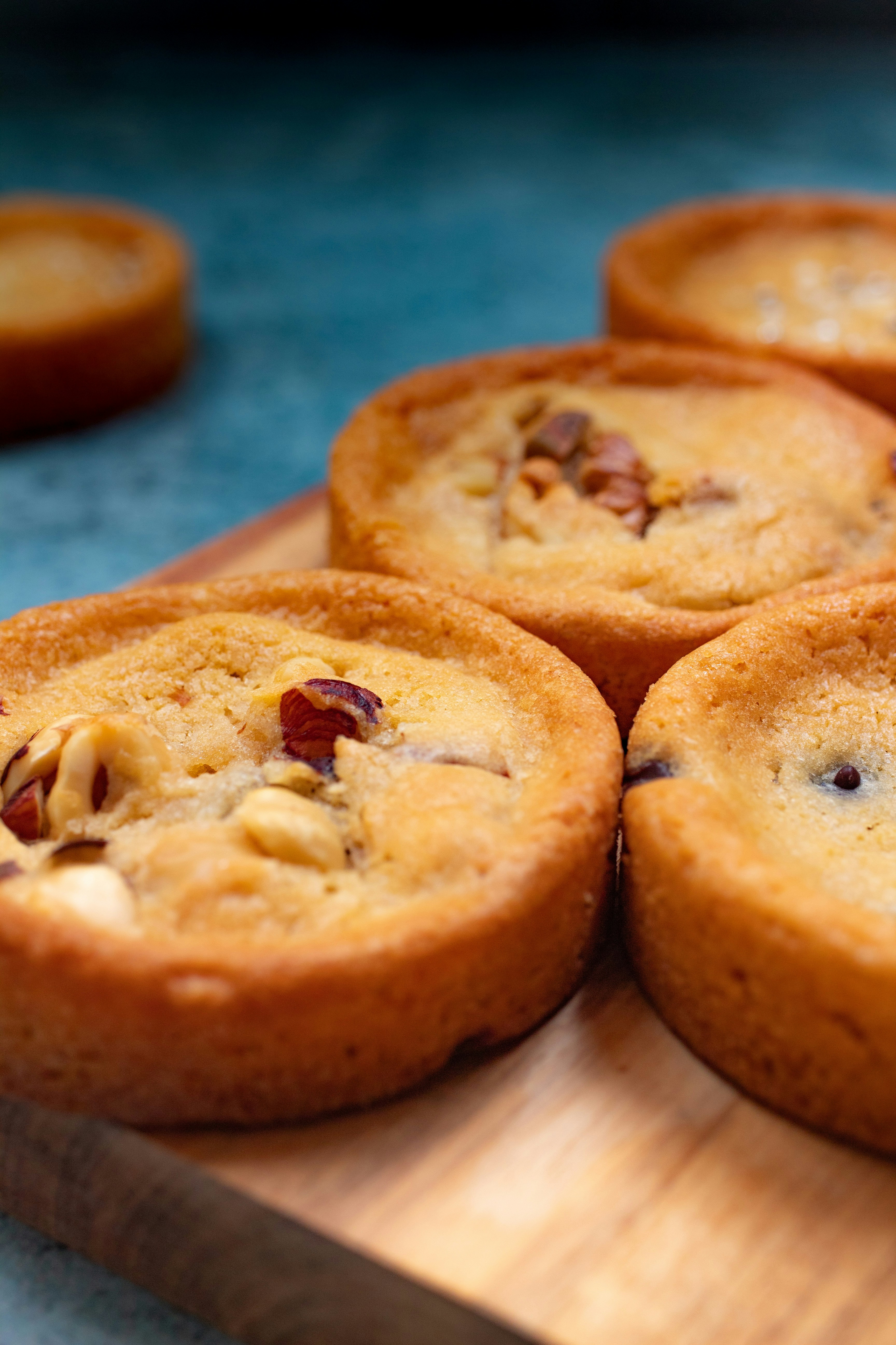 Small round nut tarts on a wooden board against a blue background
