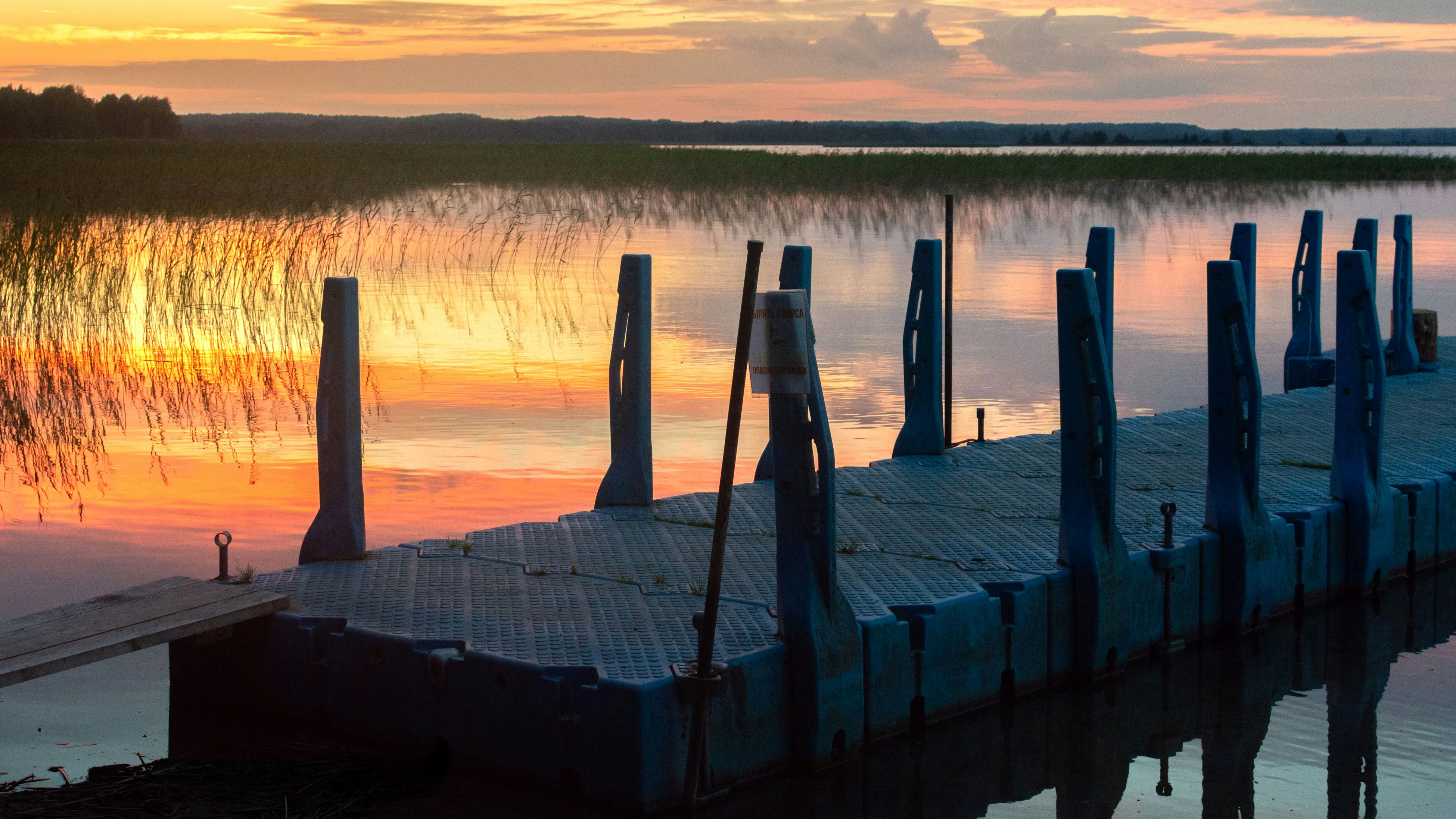 A blue floating dock on a calm lake during the golden hour