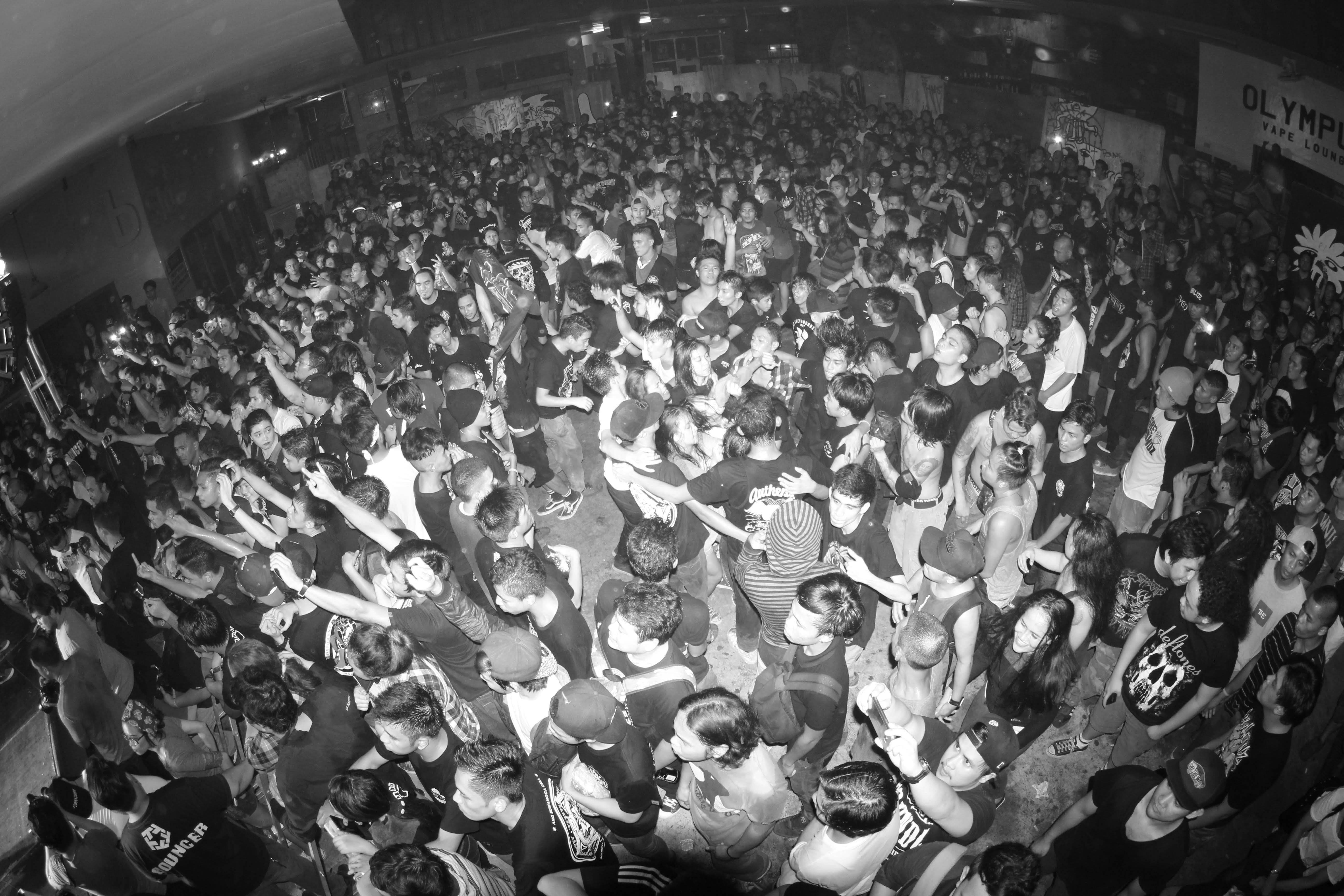 A large crowd of people at a concert in a dark indoor venue